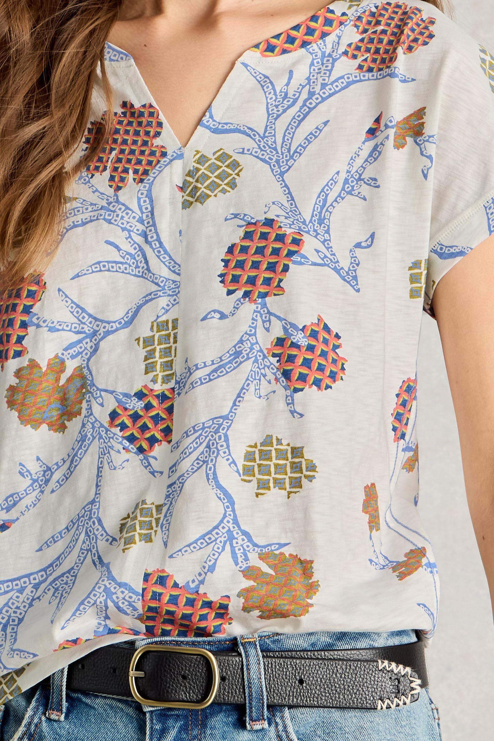 Close-up of a person wearing a patterned shirt with a belt and jeans.