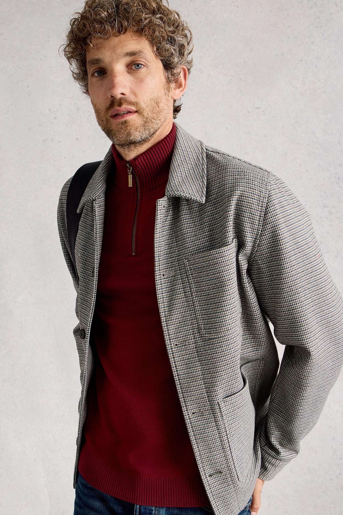 Man wearing red merino wool long sleeve knit layered under a checkered jacket