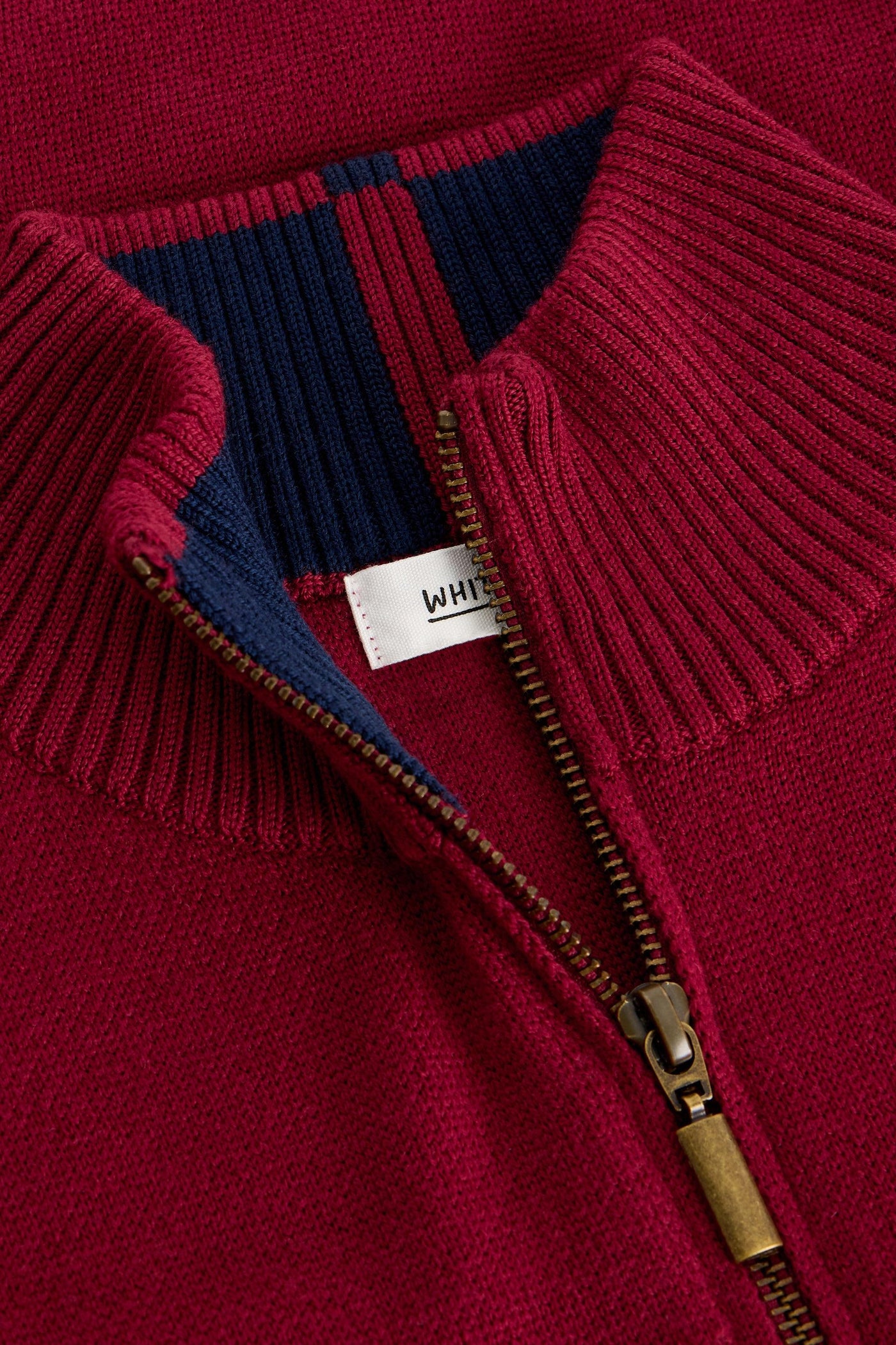 Close-up of gold quarter zip and red ribbed trim.