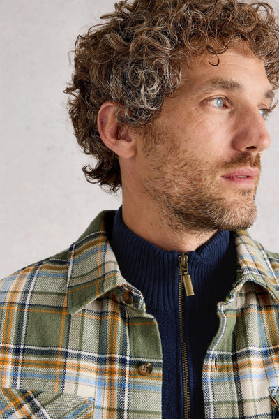 Close up of gold quarter zip layered under checkered shacket