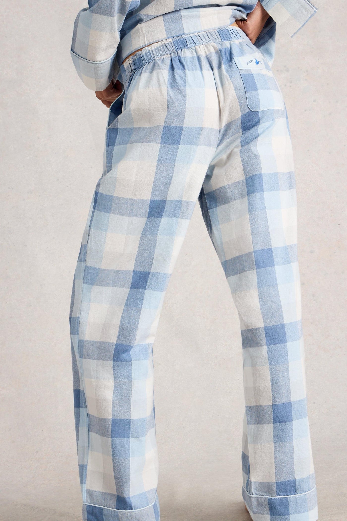 Blue and white checkered pants worn by a person on a plain background