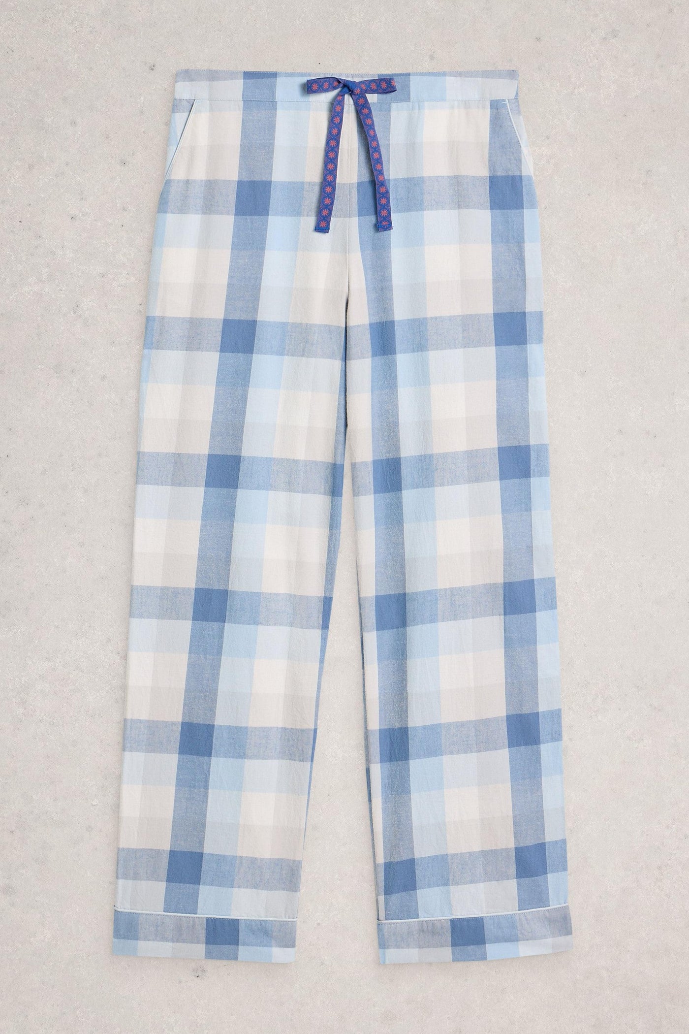 Blue and white plaid organic cotton pants with a tie waist on a light gray background