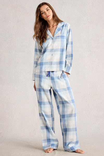 Woman wearing blue and white checkered organic cotton pyjamas on a plain background