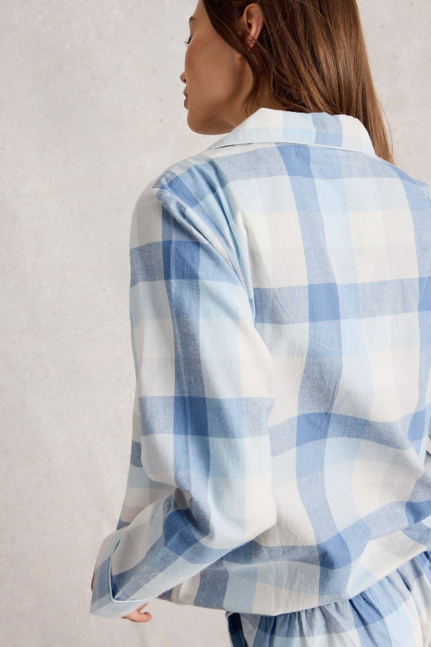 Person wearing a blue and white organic cotton shirt against a plain background