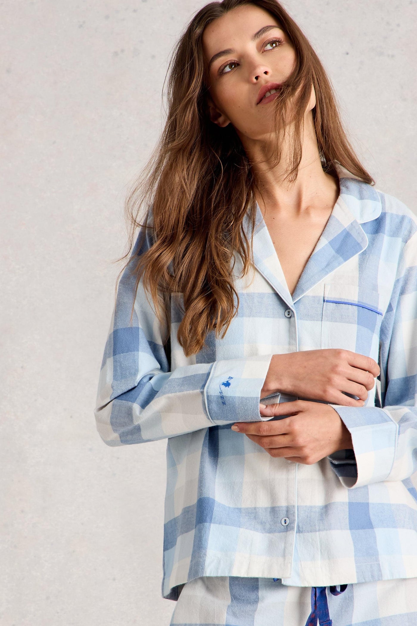 Woman wearing a blue and white checkered PJ shirt against a plain background