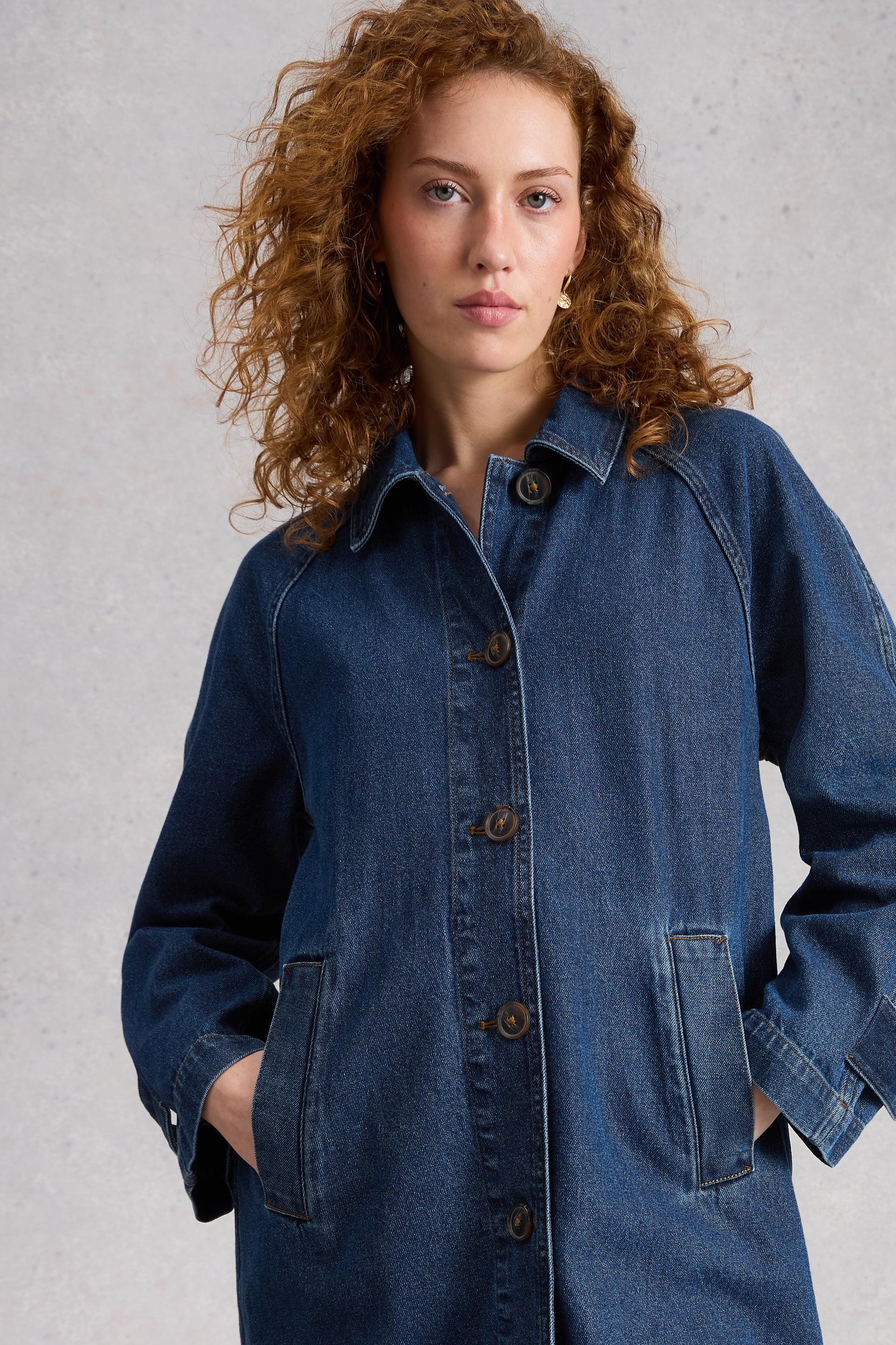 Woman wearing a blue denim organic cotton jacket against a gray background