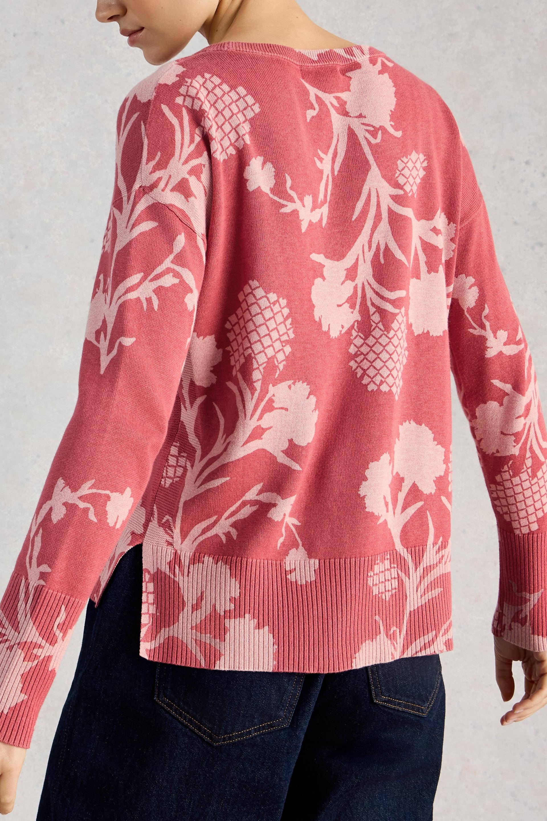 Person wearing a pink floral-patterned sweater against a neutral background