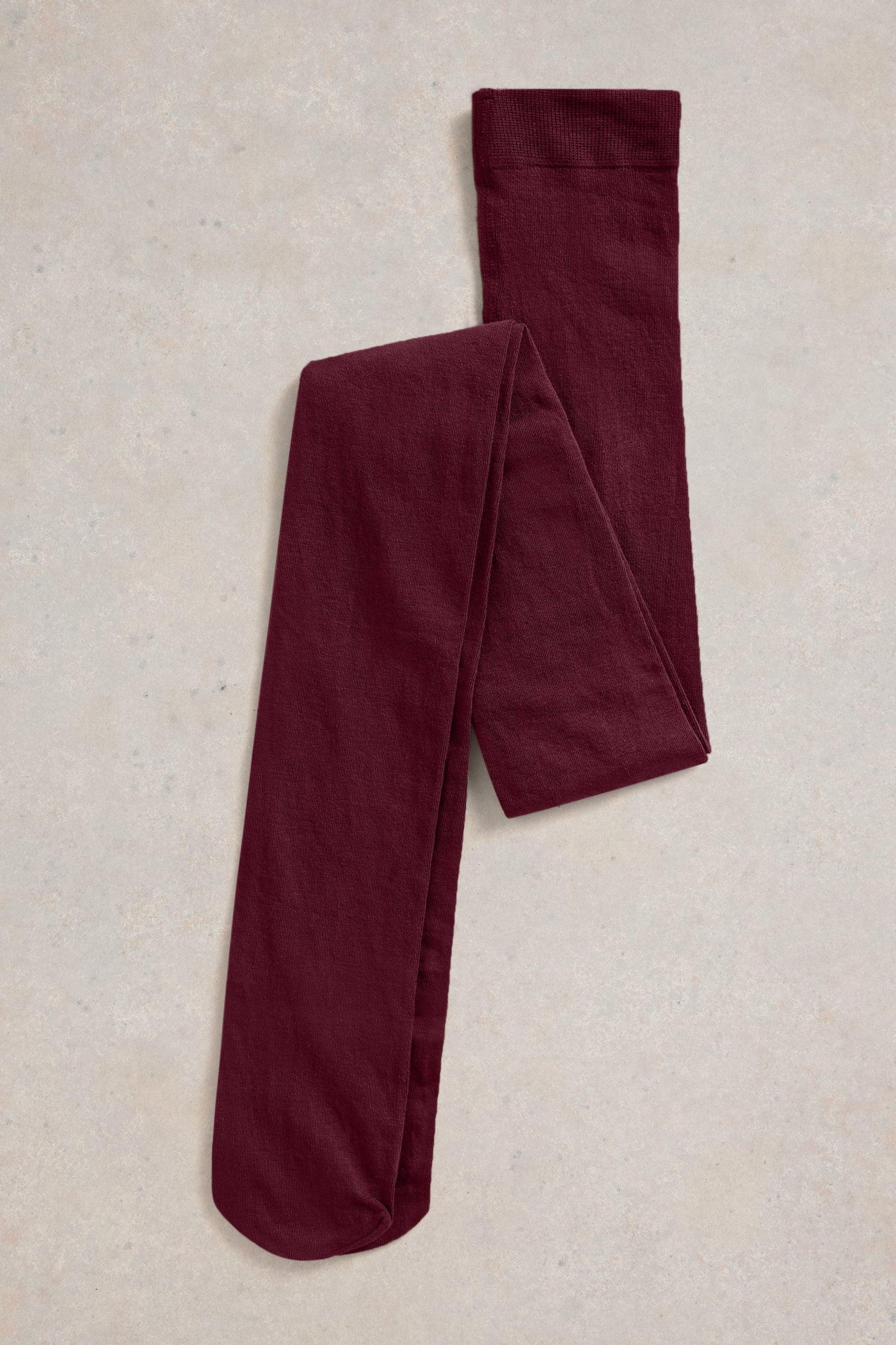 Pair of burgundy tights on a beige textured surface