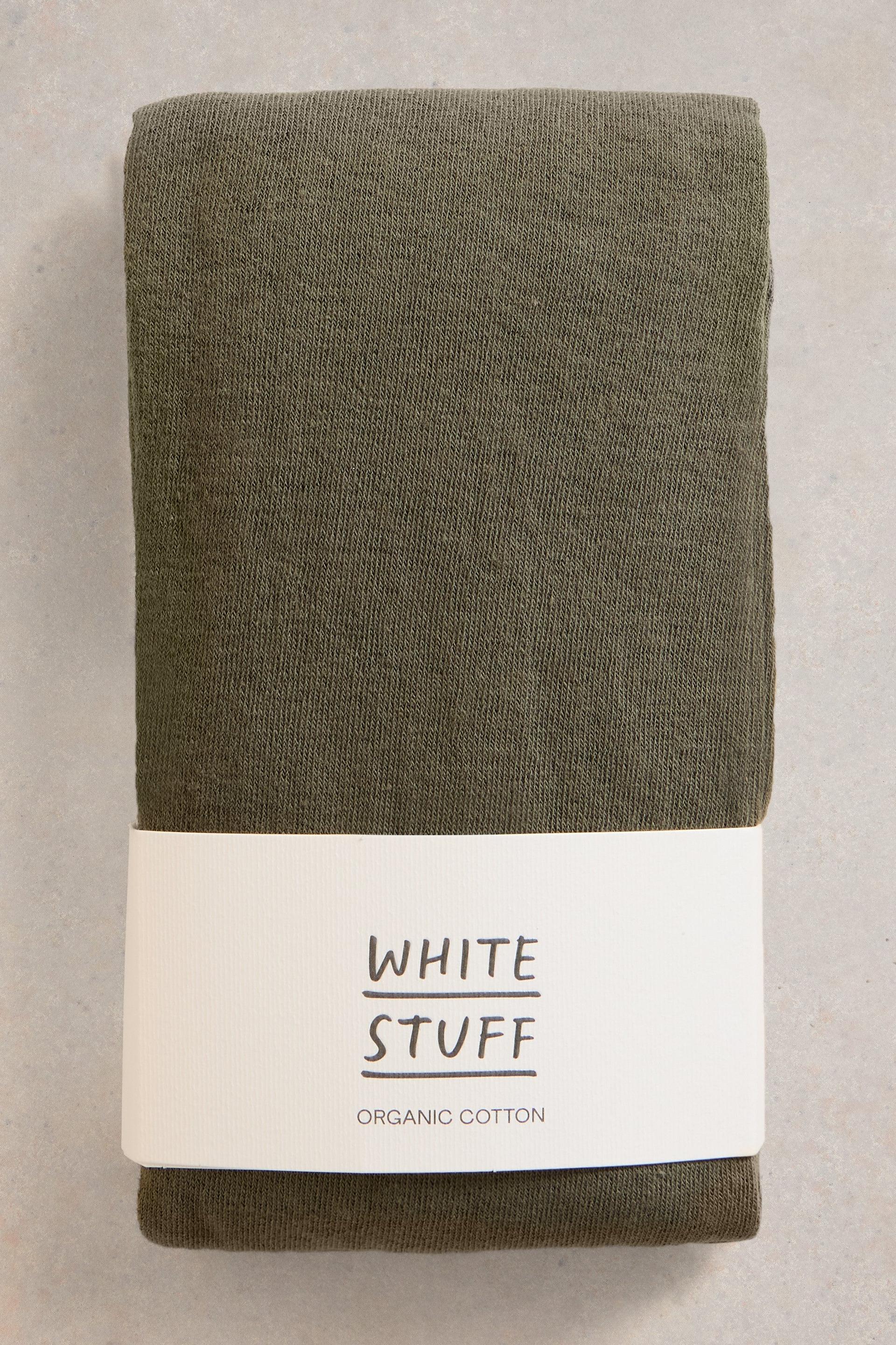 Folded green tights with a 'White Stuff' label on a light gray background