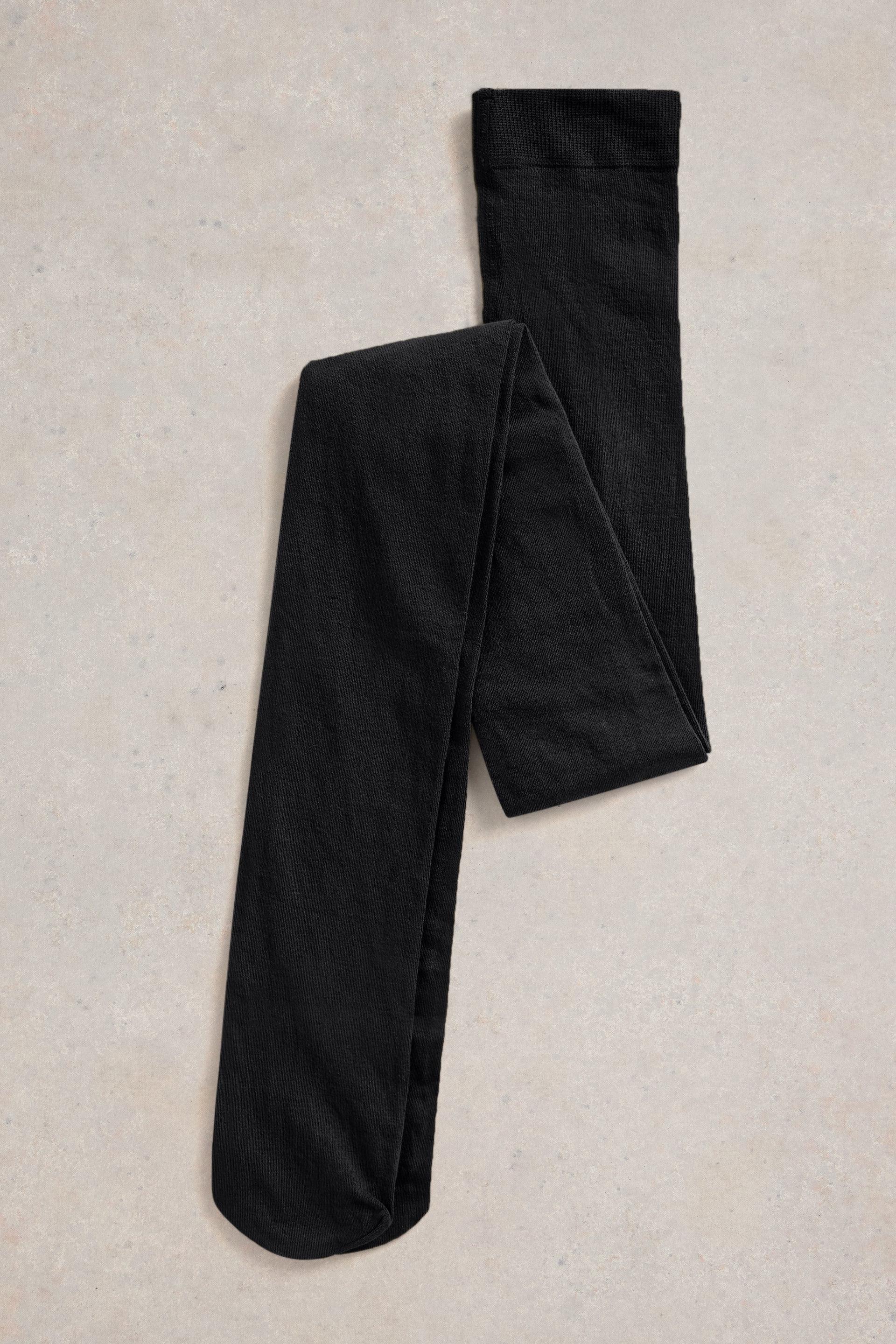 Organic cotton black tights on a beige textured surface