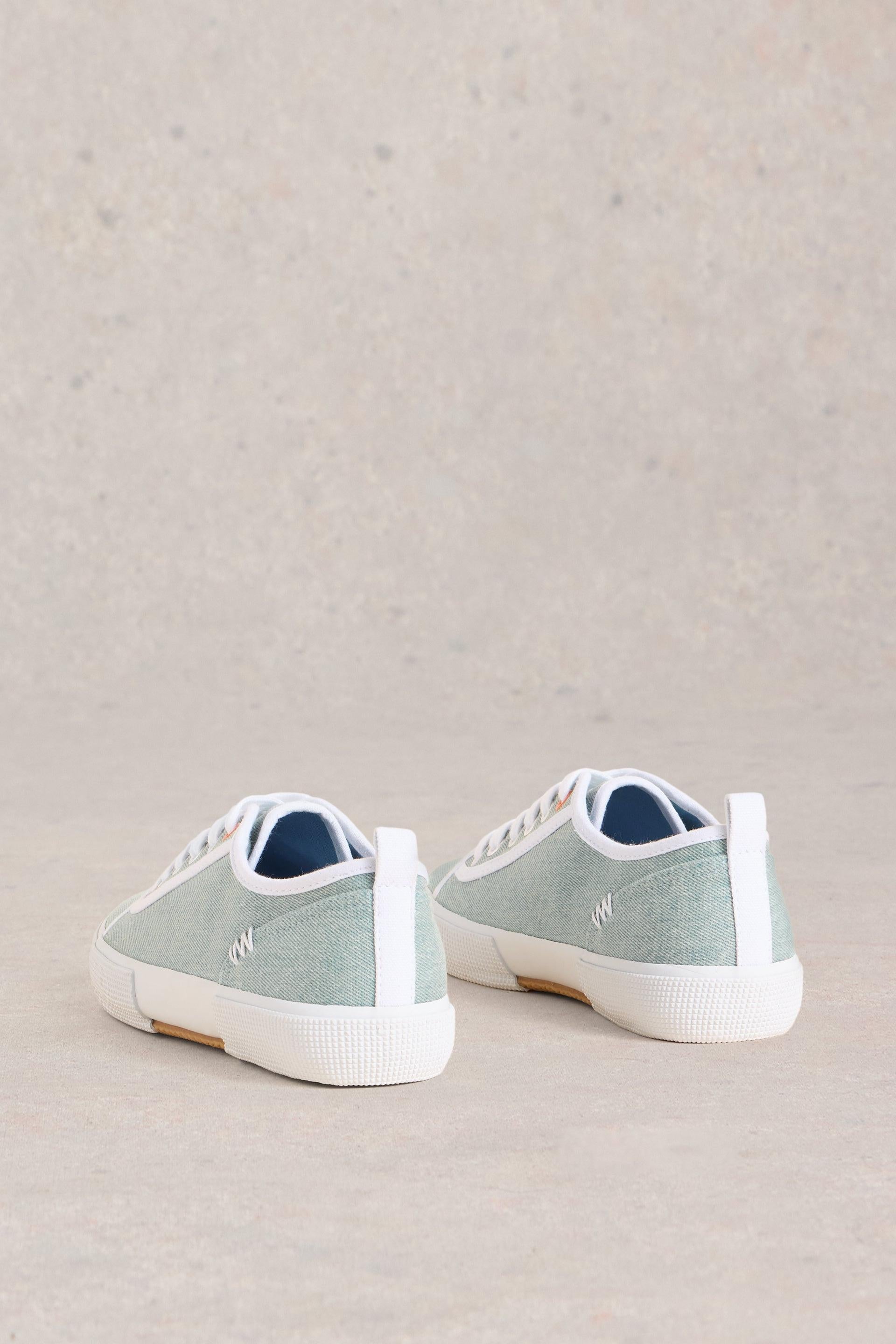 Back view of blue canvas trainers on neutral background.