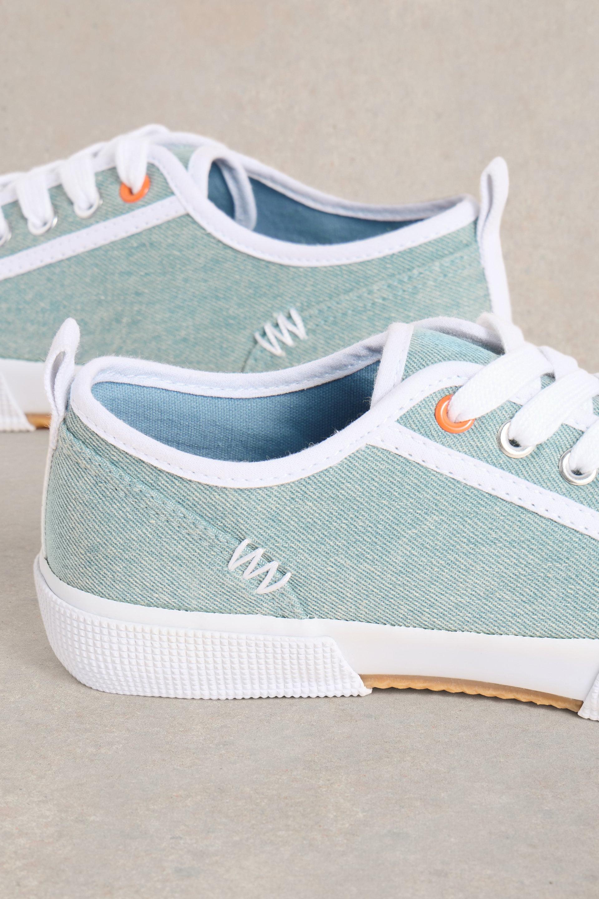 Close up of W stitching detail on blue canvas trainers.