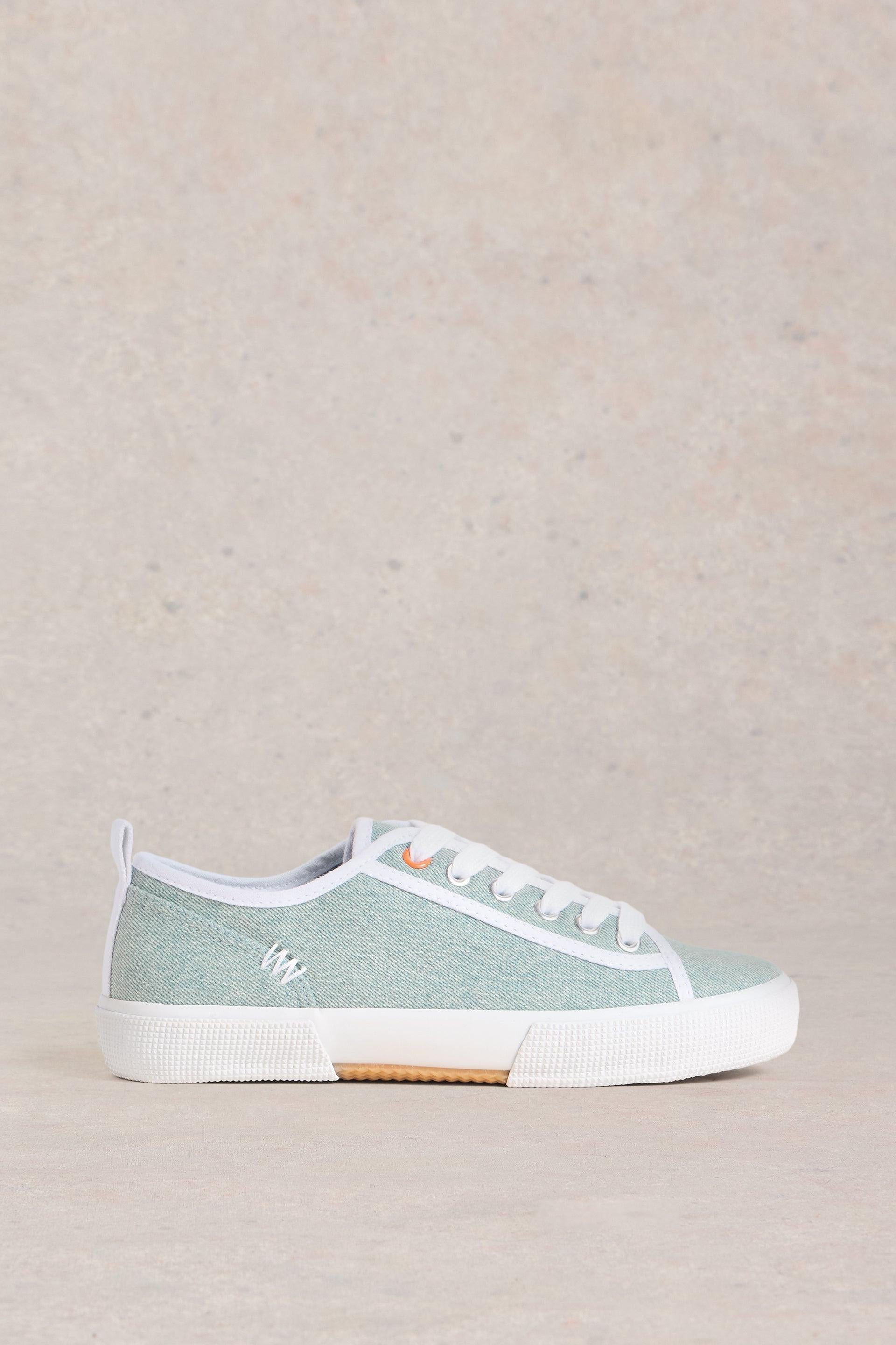 Blue canvas trainers with white trimming and laces on a neutral background.