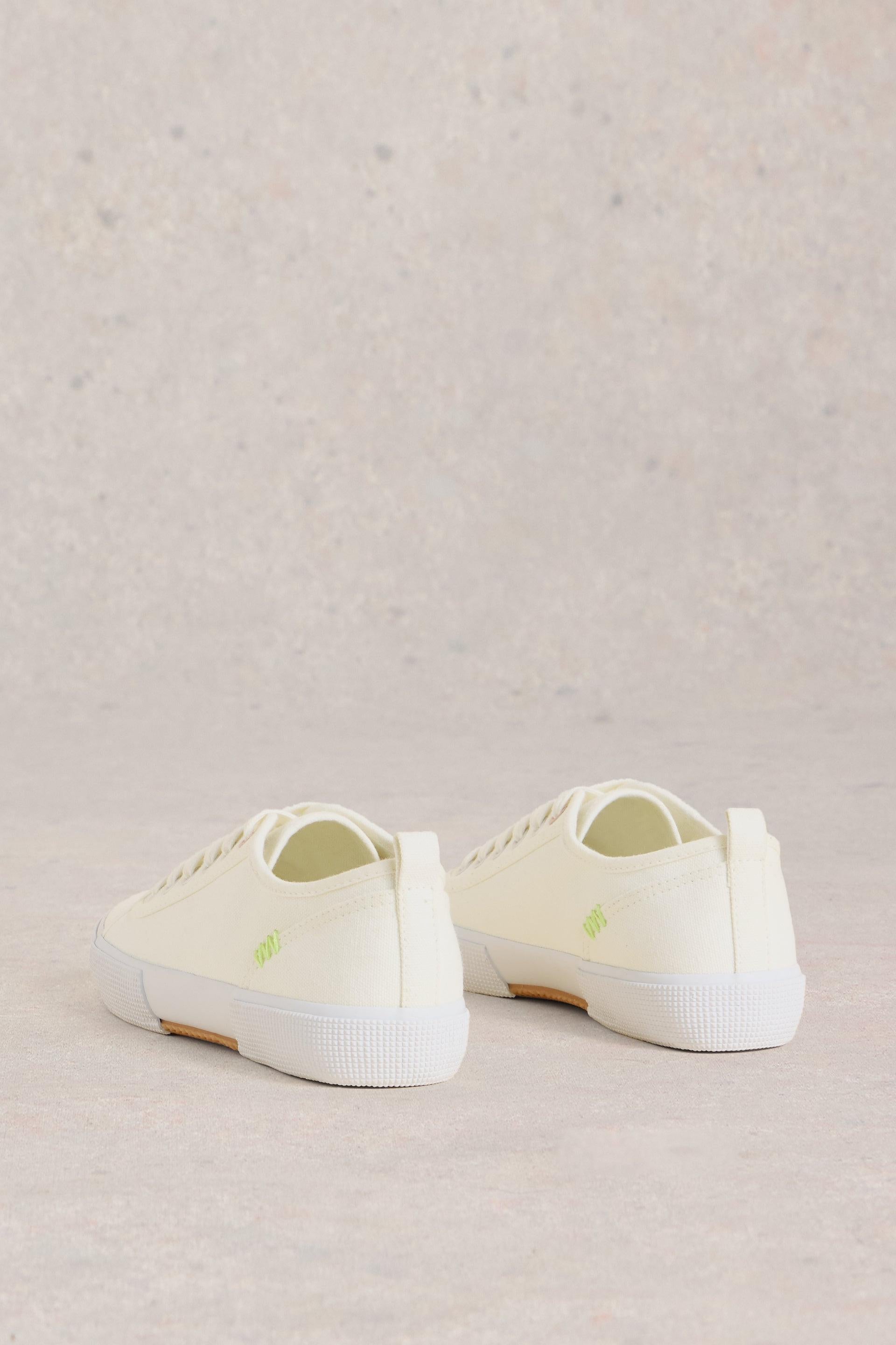 Back view of white canvas trainers showing the lime stitching.