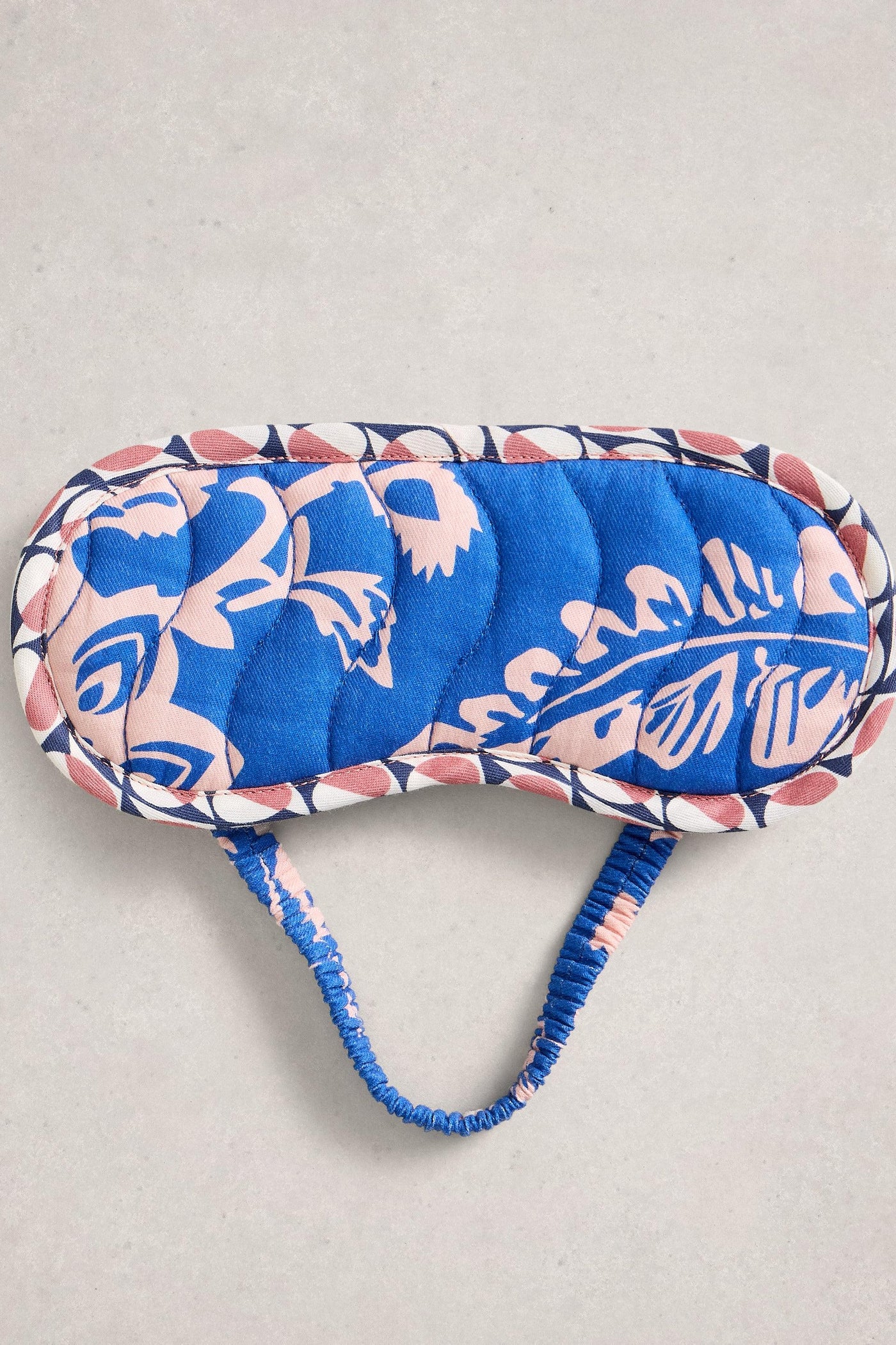 Blue and pink patterned eye mask on a light gray background