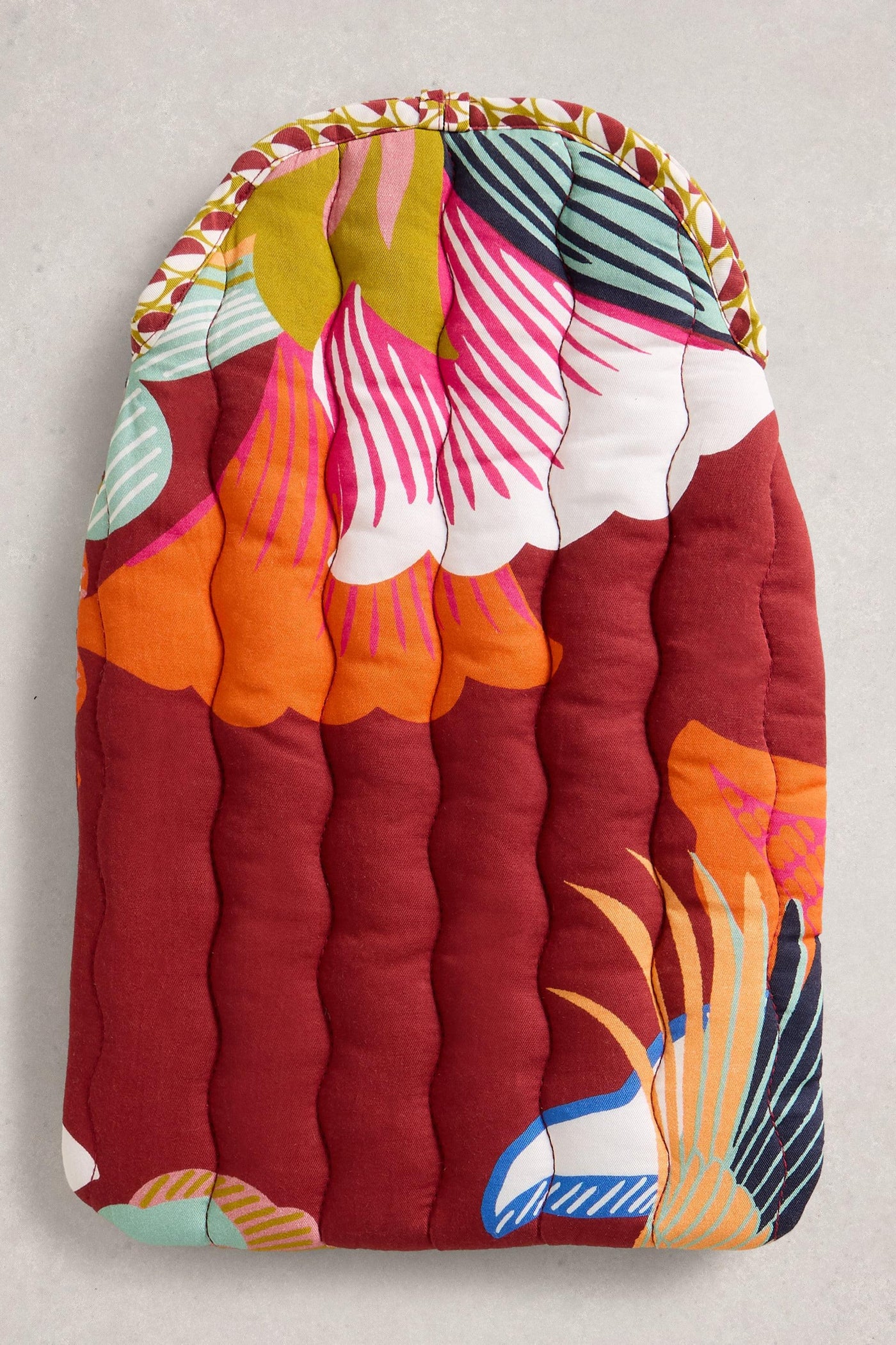 Colourful quilted hot water bottle with floral patterns on a plain background