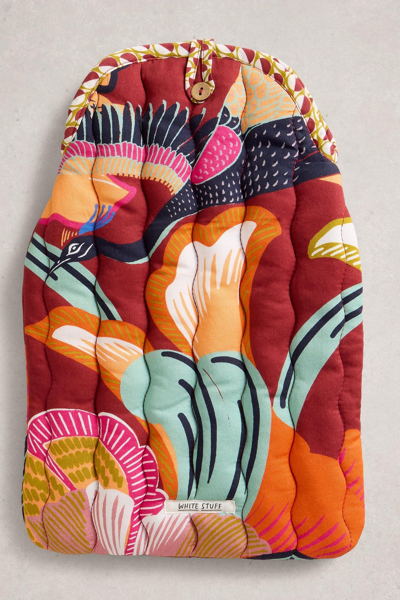 Colourful quilted hot water bottle with abstract patterns on a light gray background