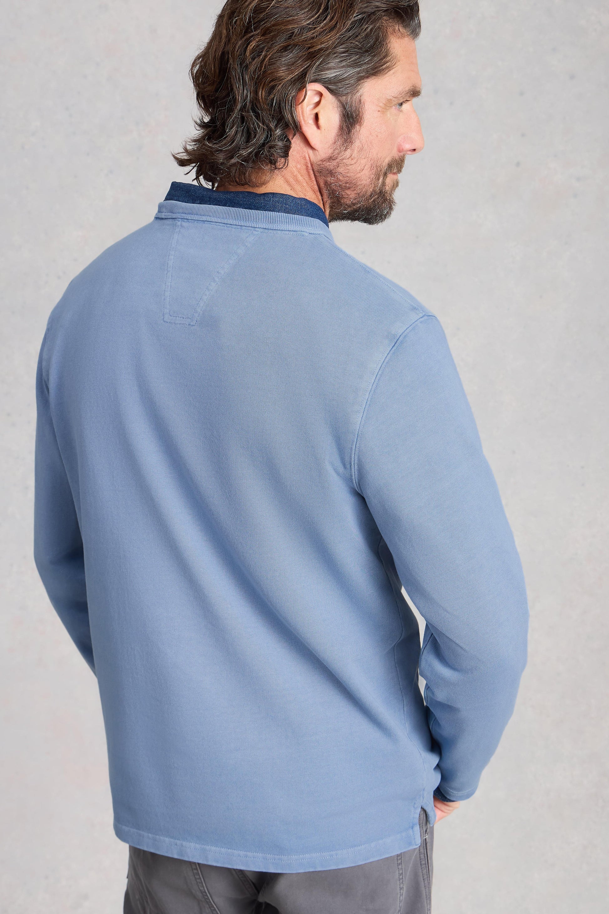 Man wearing a blue long-sleeve shirt against a gray background