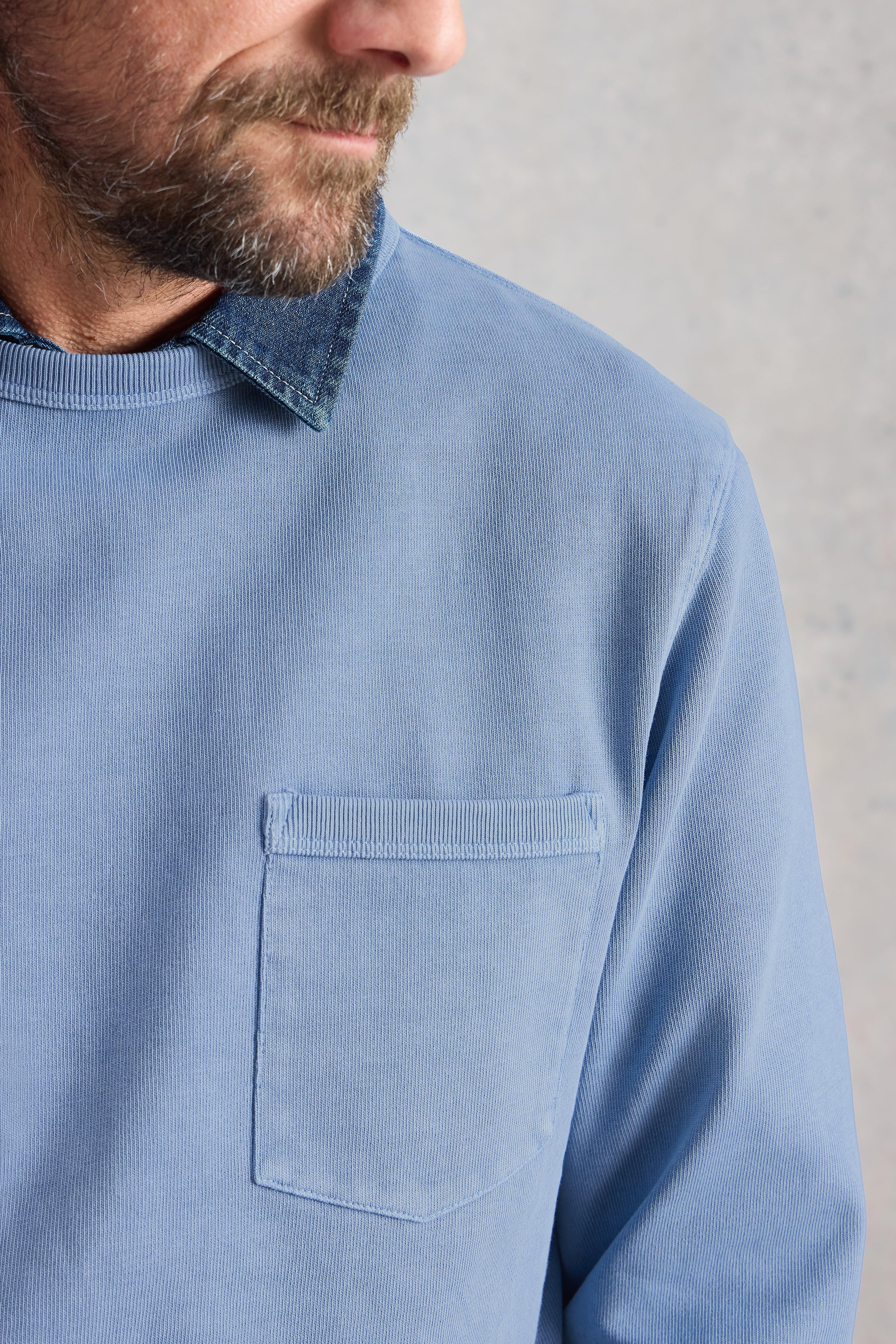 Man wearing a light blue long-sleeve shirt with a collar on a gray background