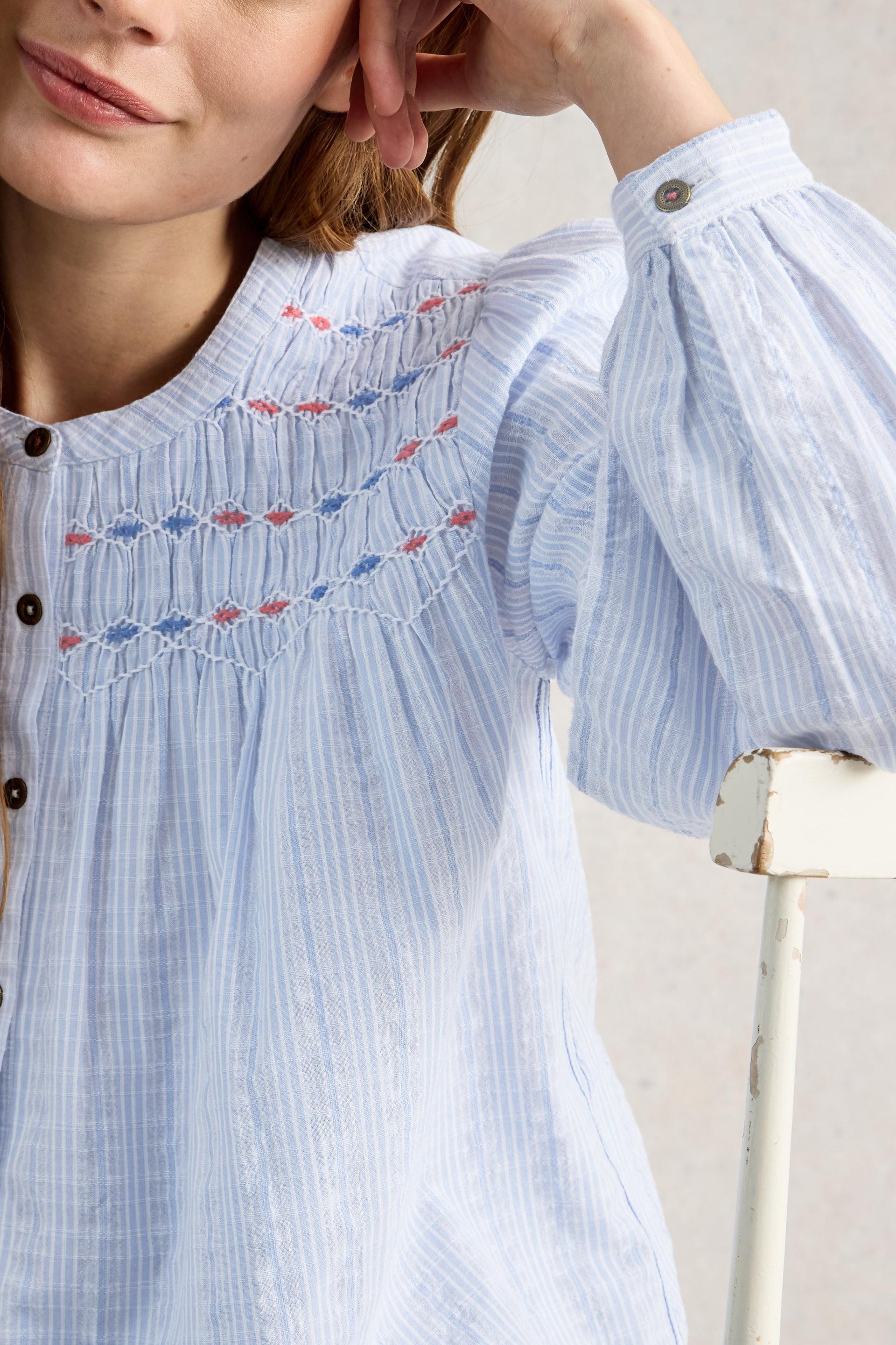 Light blue striped blouse with embroidered details worn by a person.