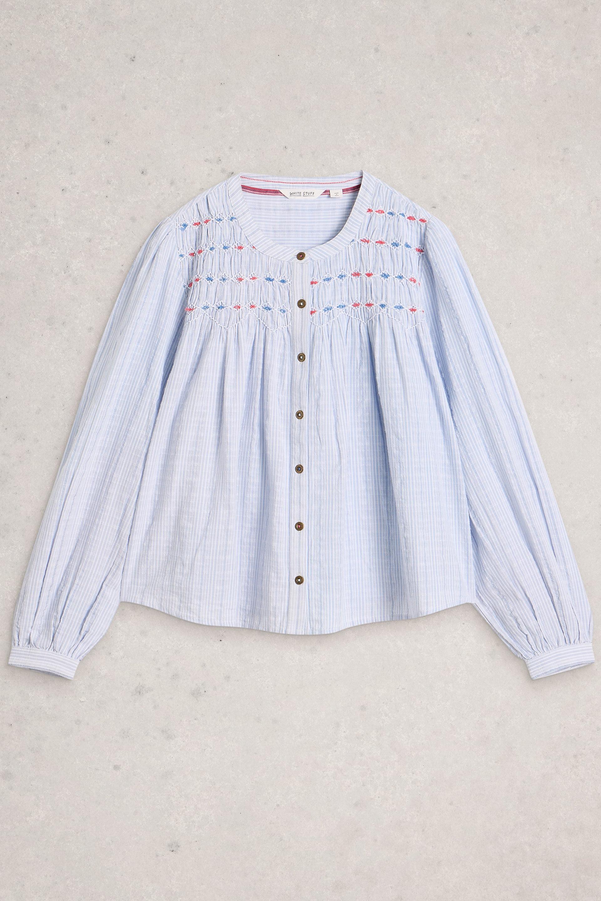 Light blue striped blouse with embroidered details on a beige background