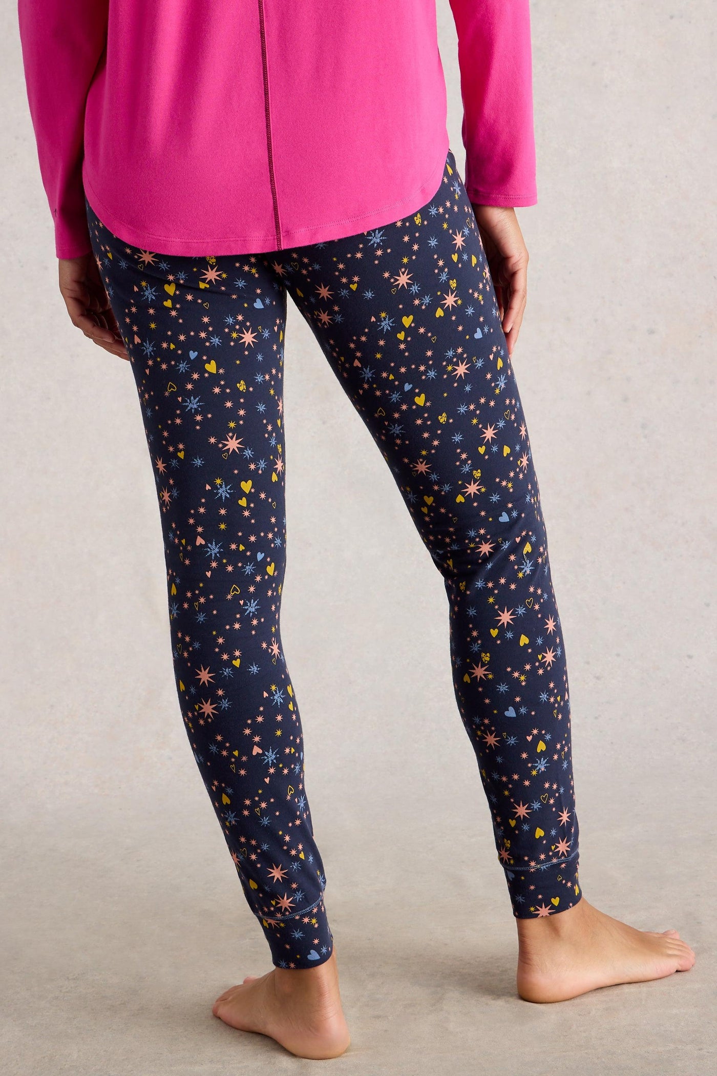 Person wearing navy leggings with star pattern and pink top on a neutral background