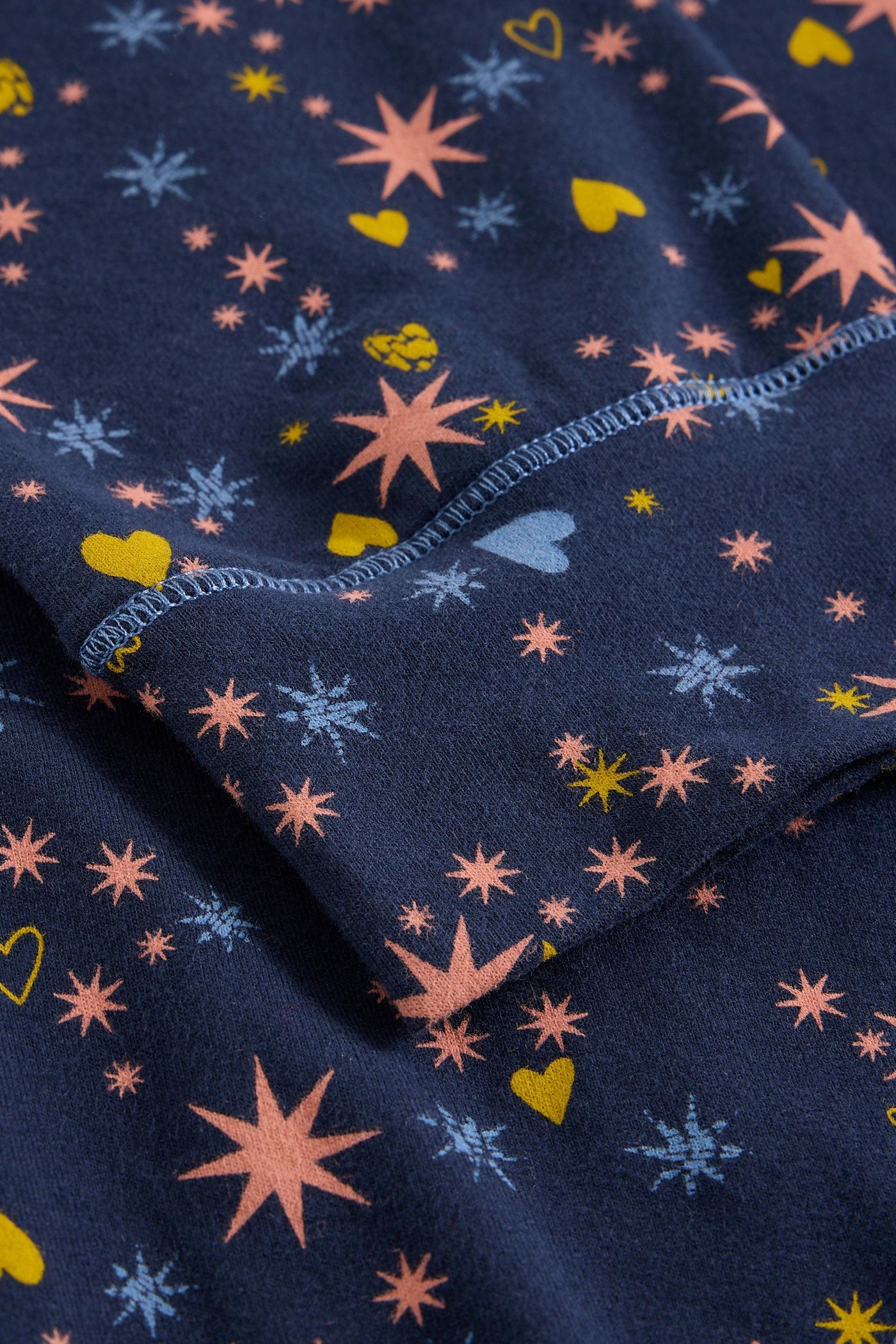 Navy organic cotton fabric with colourful star, heart, and snowflake patterns