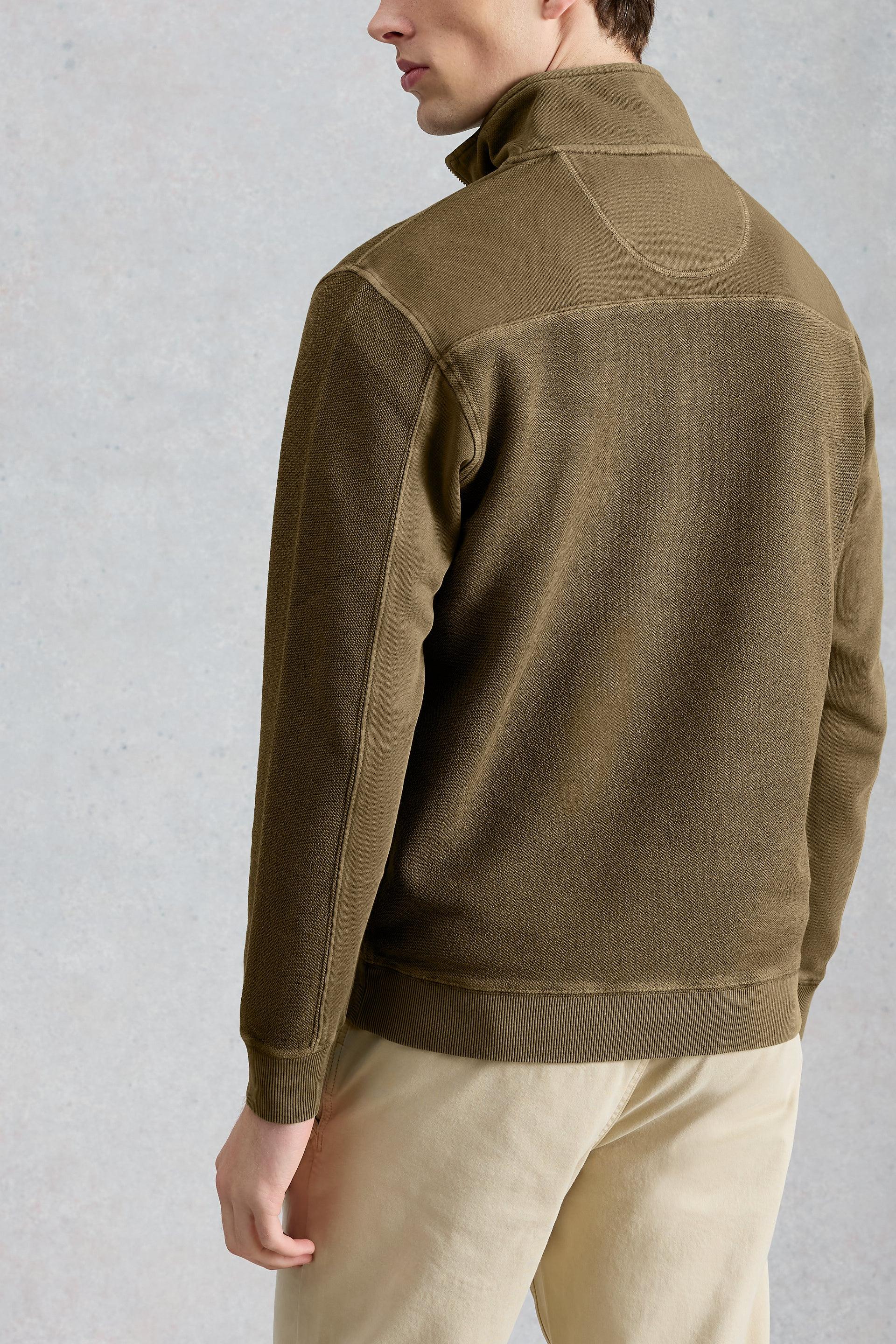 Model wearing a khaki half zip jumper against a gray background
