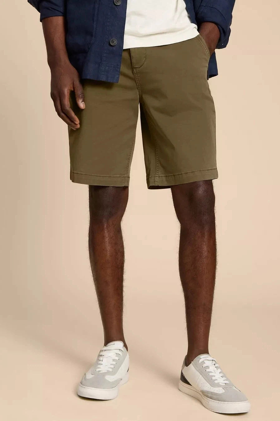 Model wearing khaki organic cotton chino shorts paired with white trainers