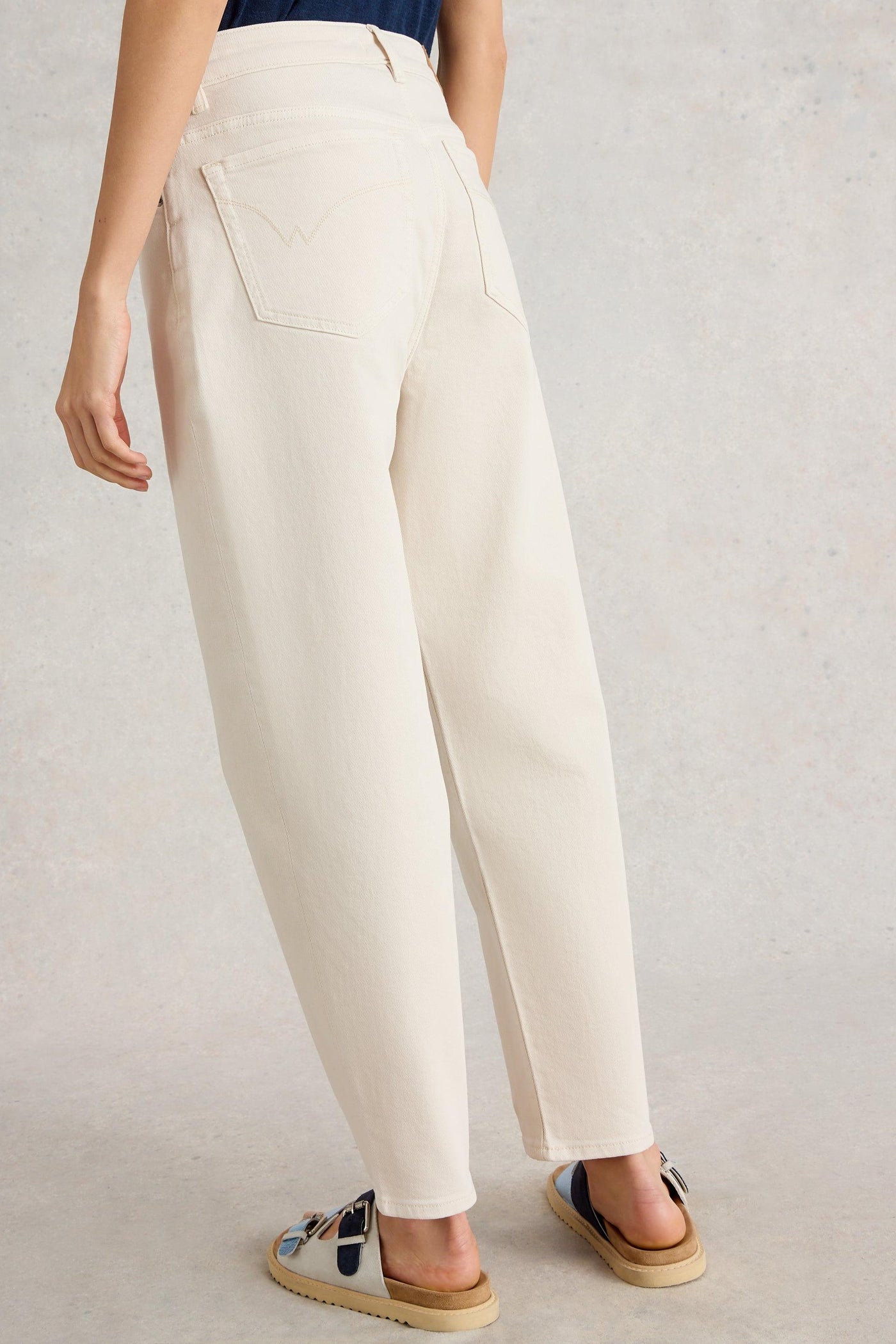 Back view of tapered ankle-length jeans in natural white organic cotton with classic pockets