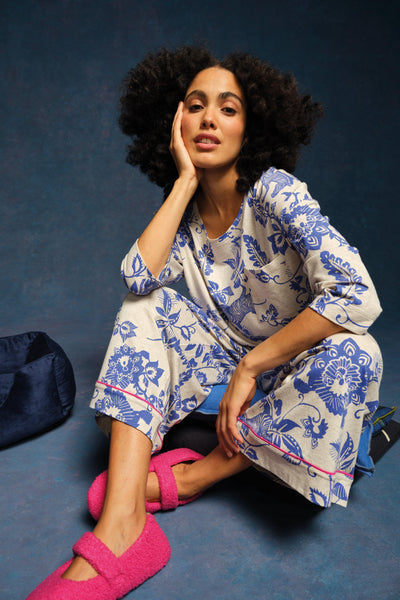 Woman wearing a blue floral pyjamas sitting on a blue floor with a dark blue background