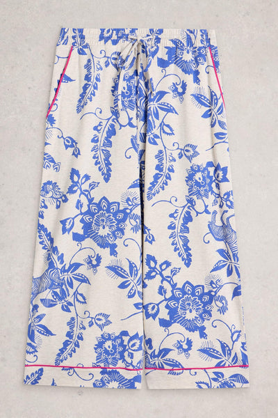 White organic cotton pants with blue floral pattern on a gray background