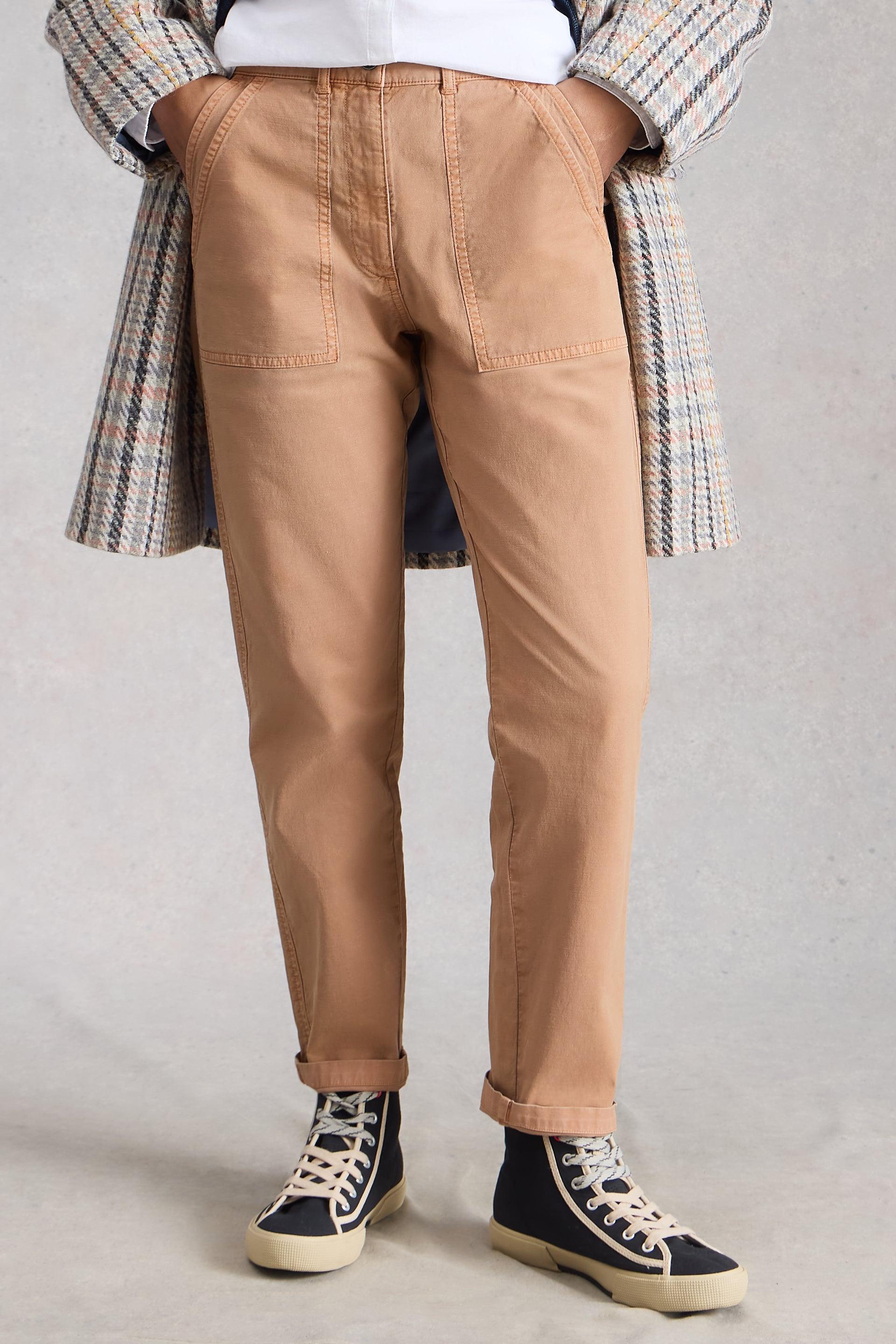 Person wearing beige organic cotton pants and a plaid coat on a plain background