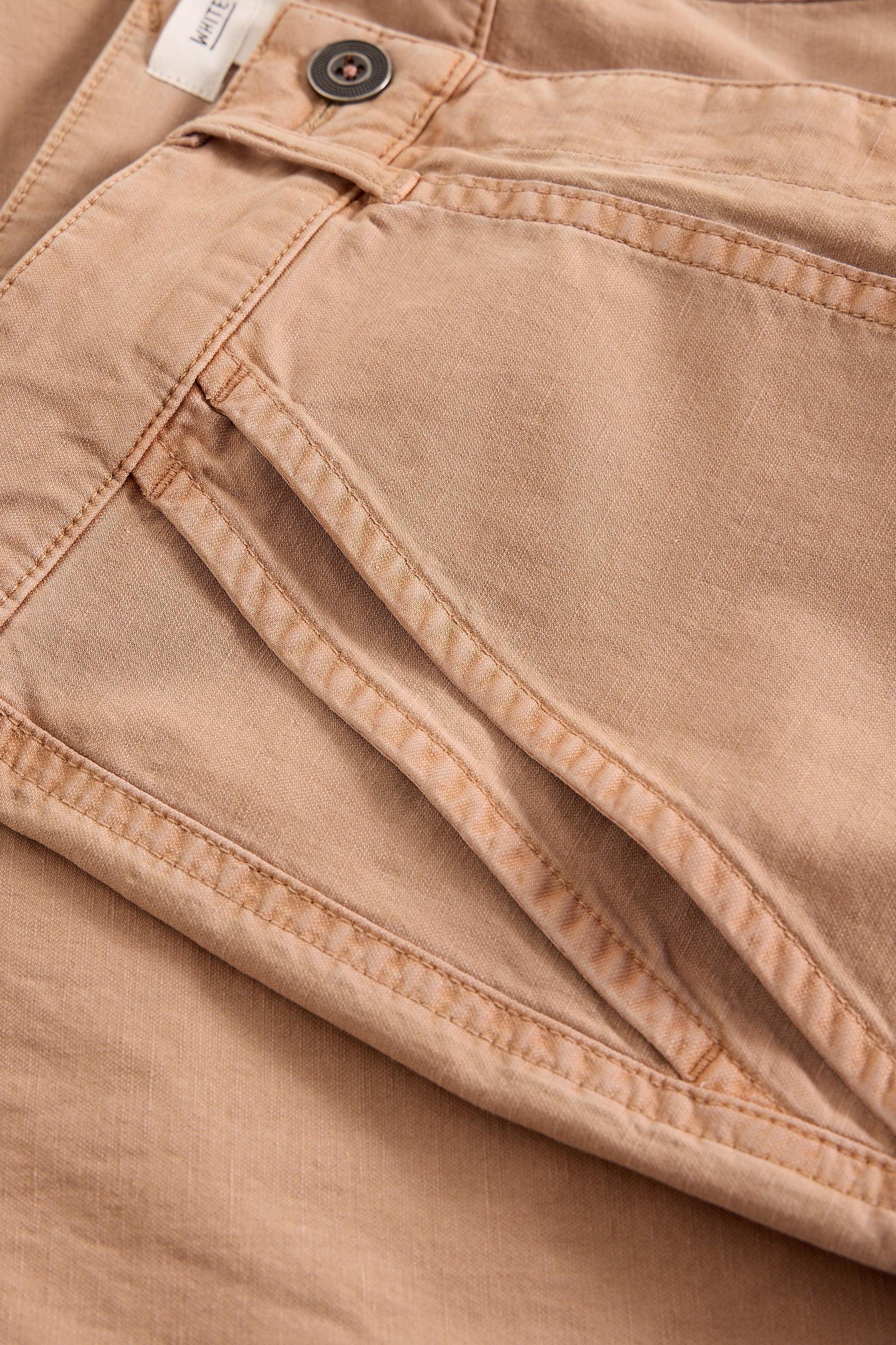 Close-up of beige pants with a button and zipper detail.