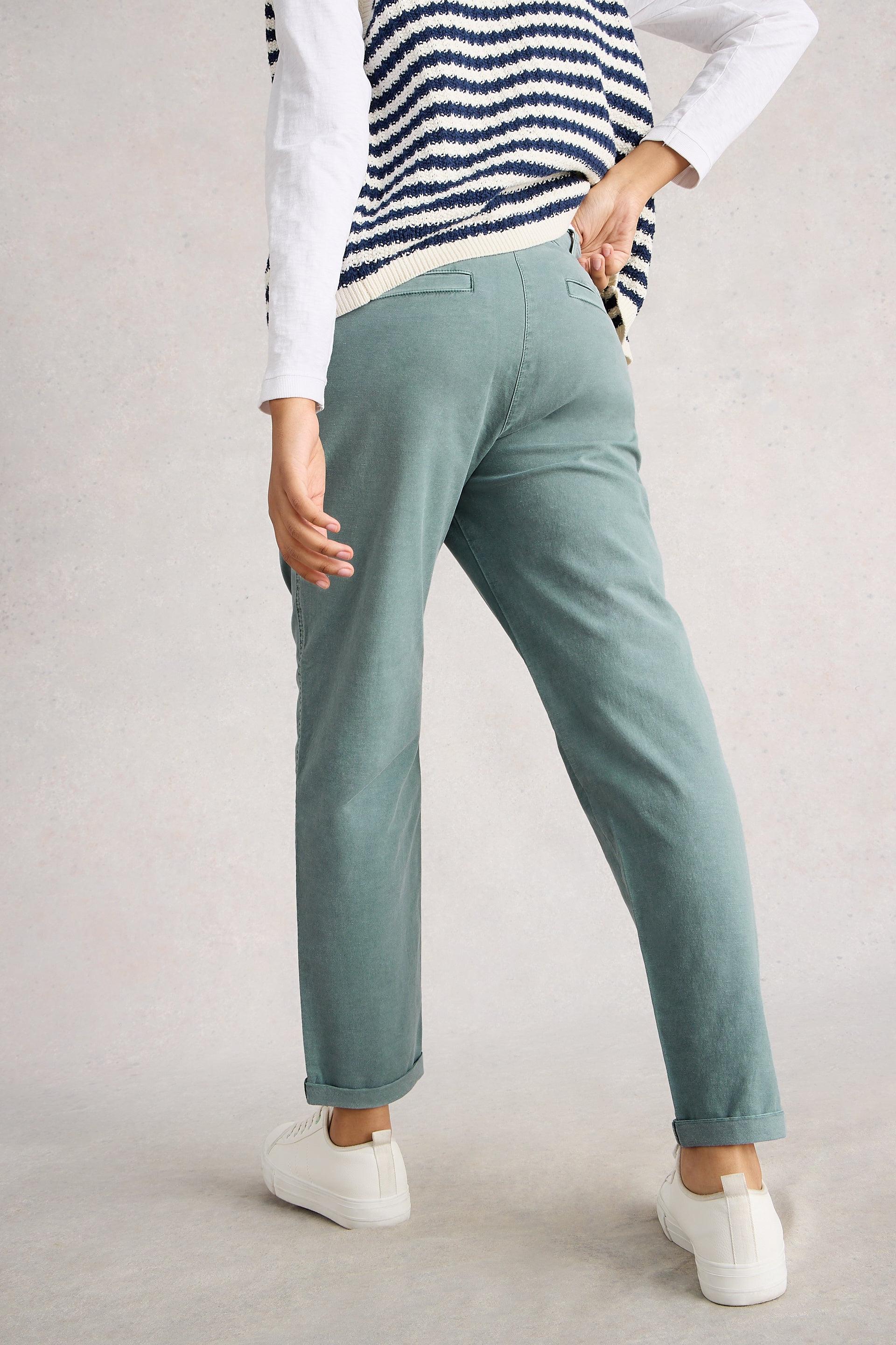 Person wearing blue tapered chinos and a striped sweater on a plain background