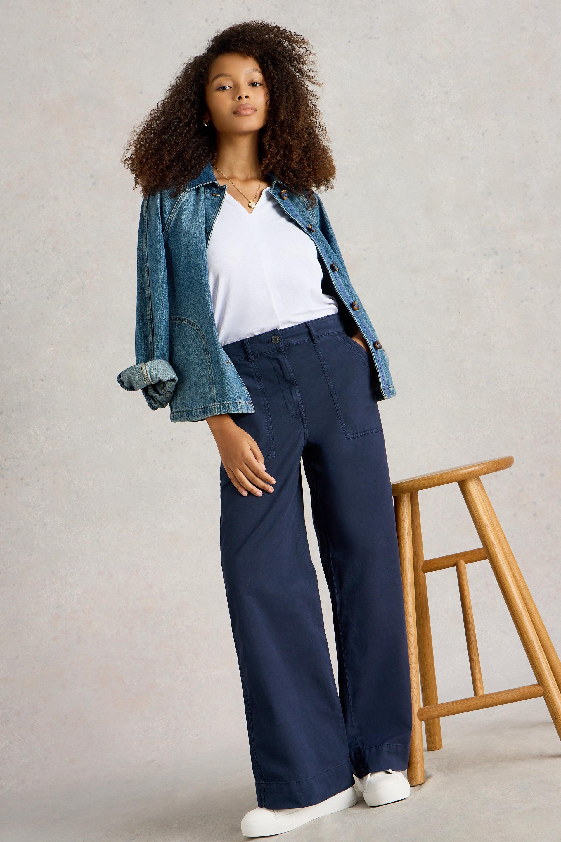 Model wearing the White Stuff Twister Chino Wide Leg Trouser in Dark Navy, paired with white t-shirt and denim jacket.