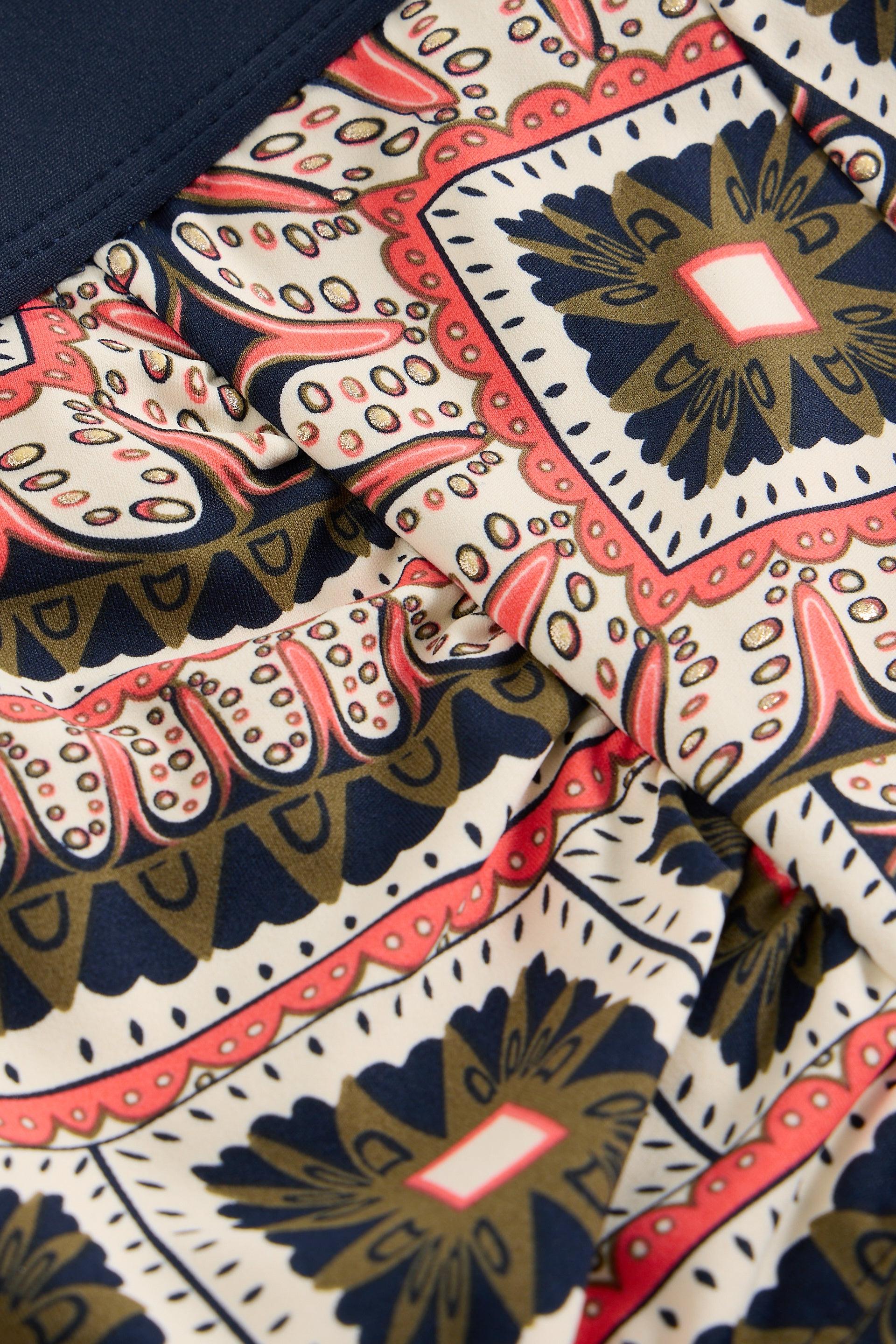 Close-up of a patterned fabric with geometric designs in navy, red, and gold.