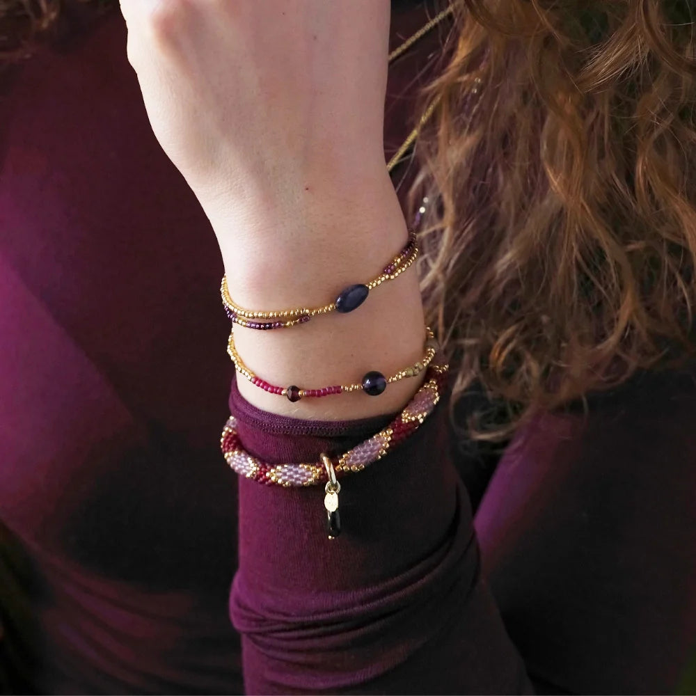 A woman wearing a stack of beaded amethyst gemstone bracelets on her wrist.