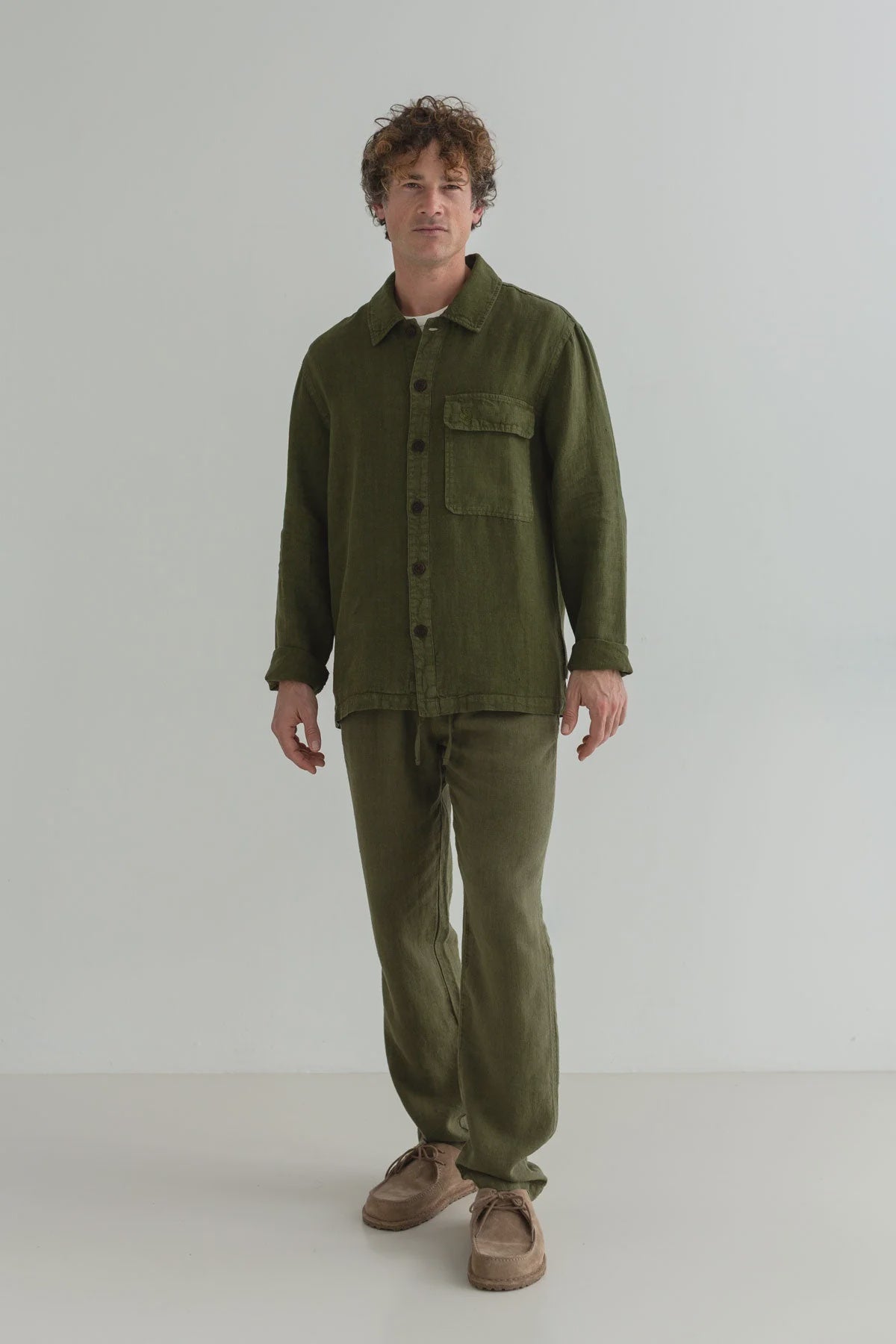 Man wearing an olive green shirt and pants on a white background