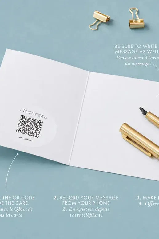 Open card with QR code, pen, and paper clips on a light blue background
