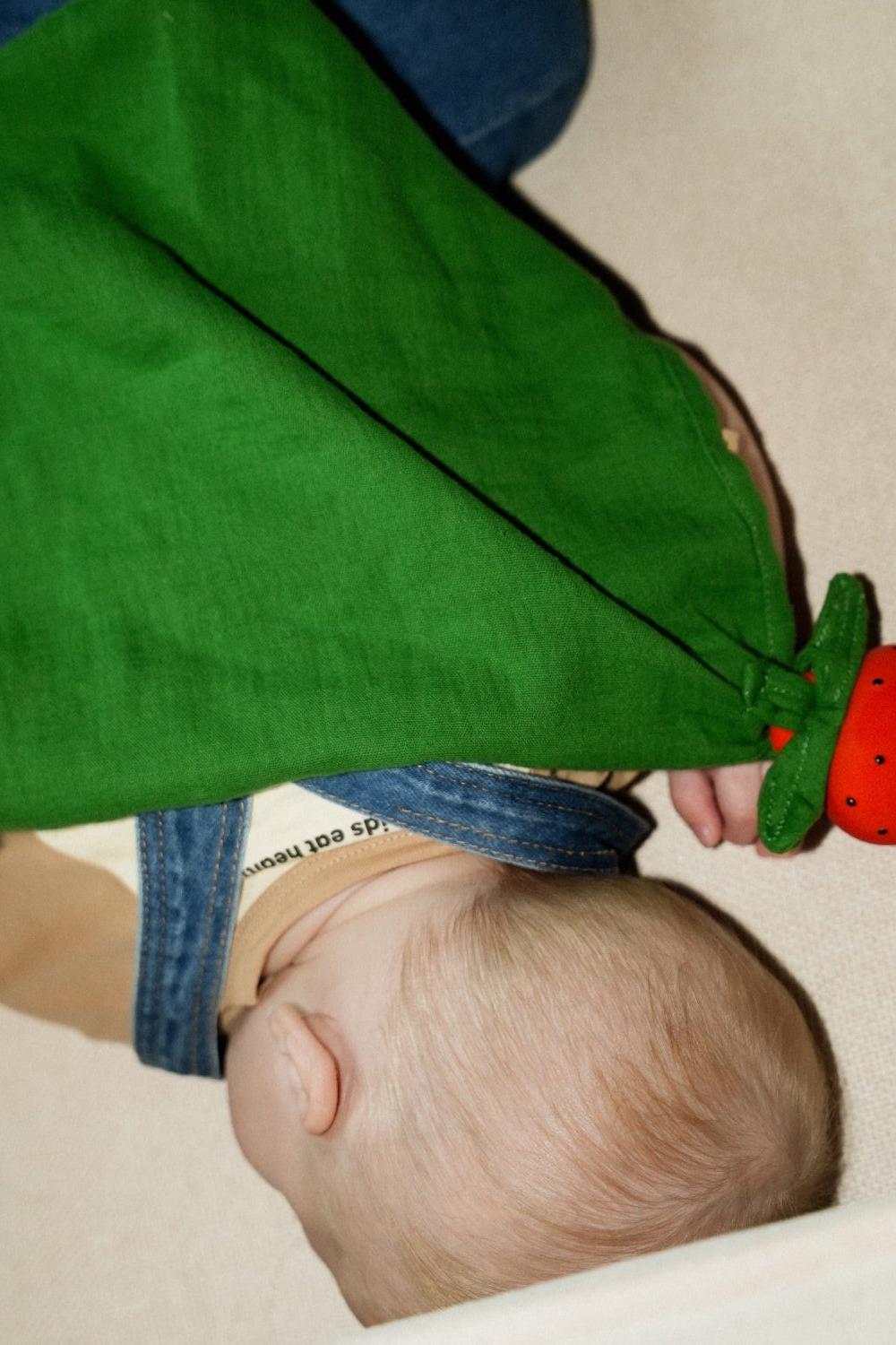 Baby playing with a handcrafted baby doudou, strawberry design, safe and sustainable, organic cotton and food-grade natural rubber.