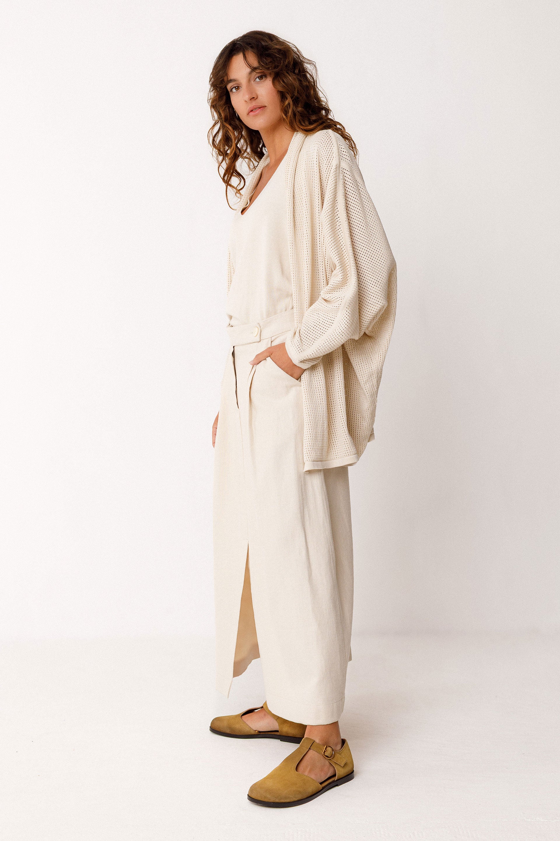 Woman wearing a beige outfit with an organic cotton cardigan and pants on a white background
