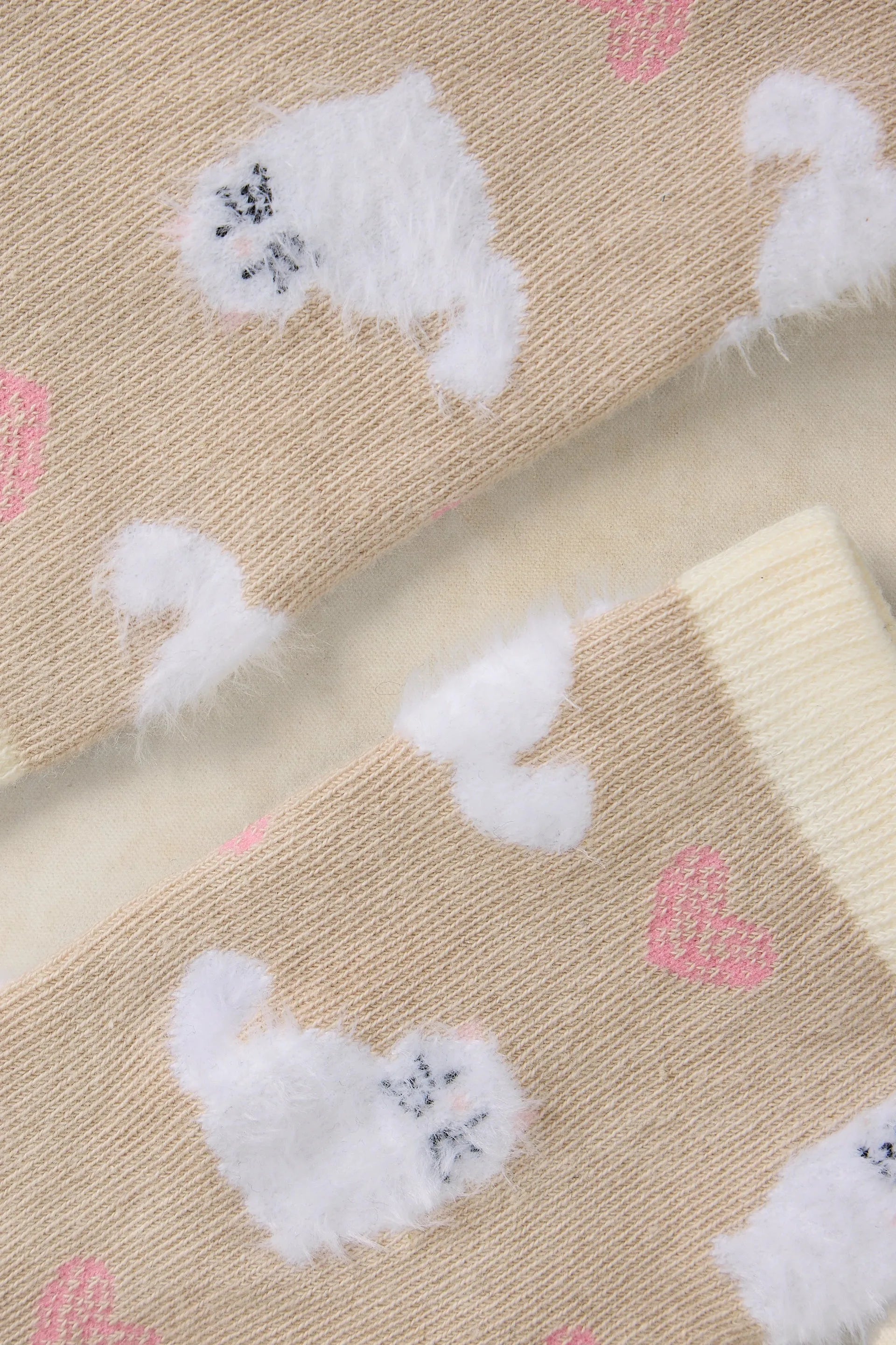 Beige socks with white cats and pink heart patterns on a beige background