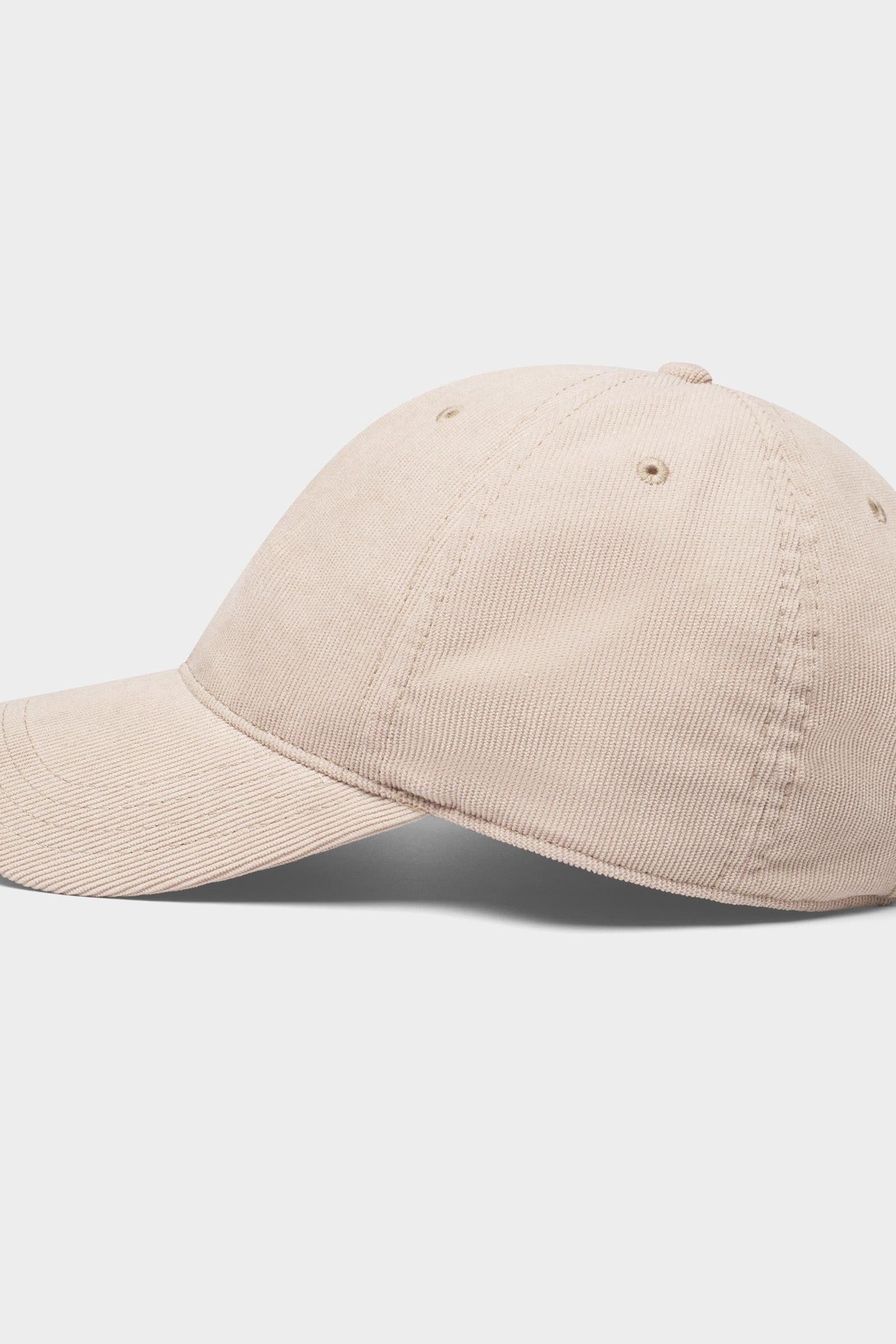 A light beige washed cotton baseball cap shown from a side profile view against a clean, light gray background.