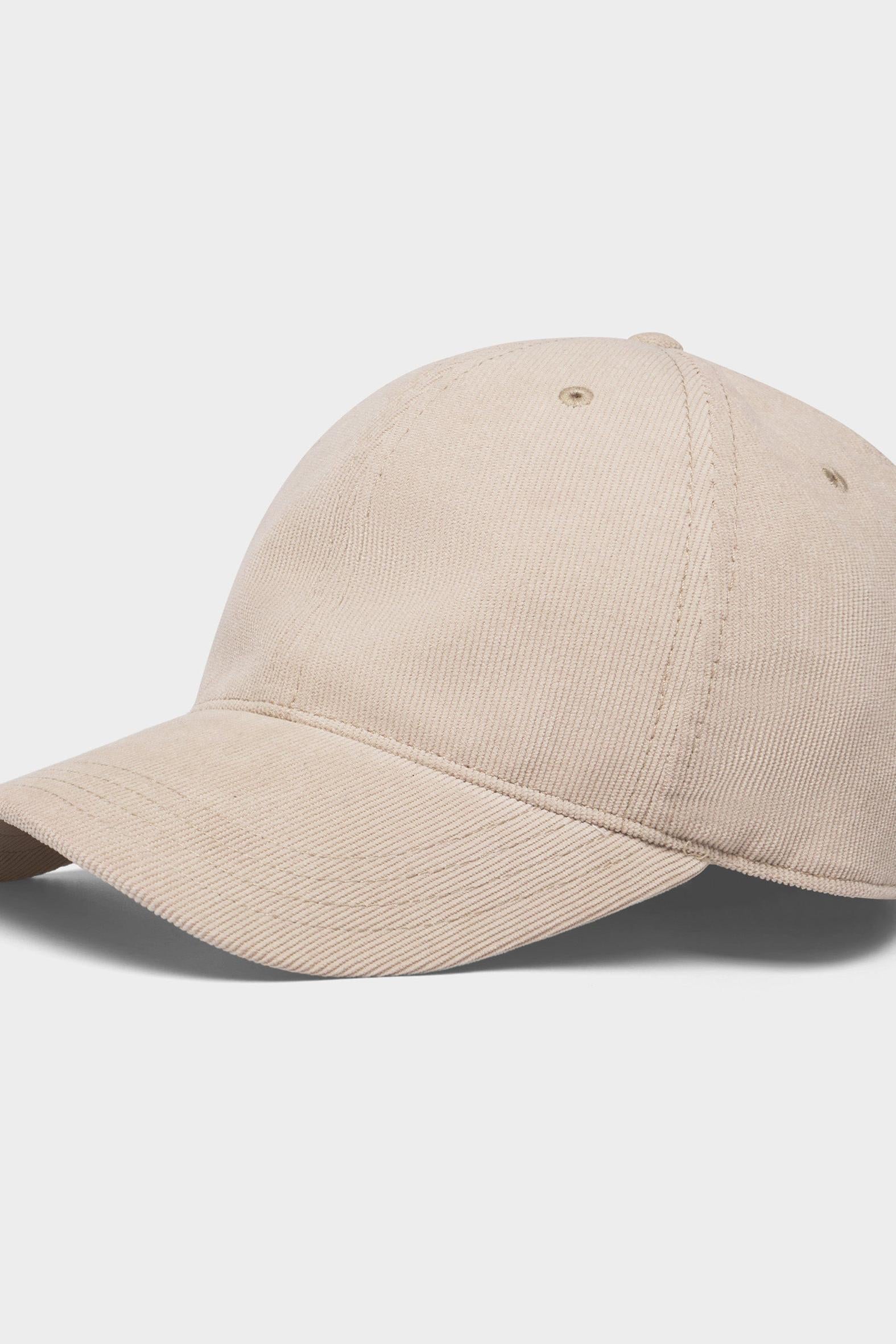 A classic six-panel baseball cap in a light beige or sand color, shown from a three-quarters angle on a light gray background.