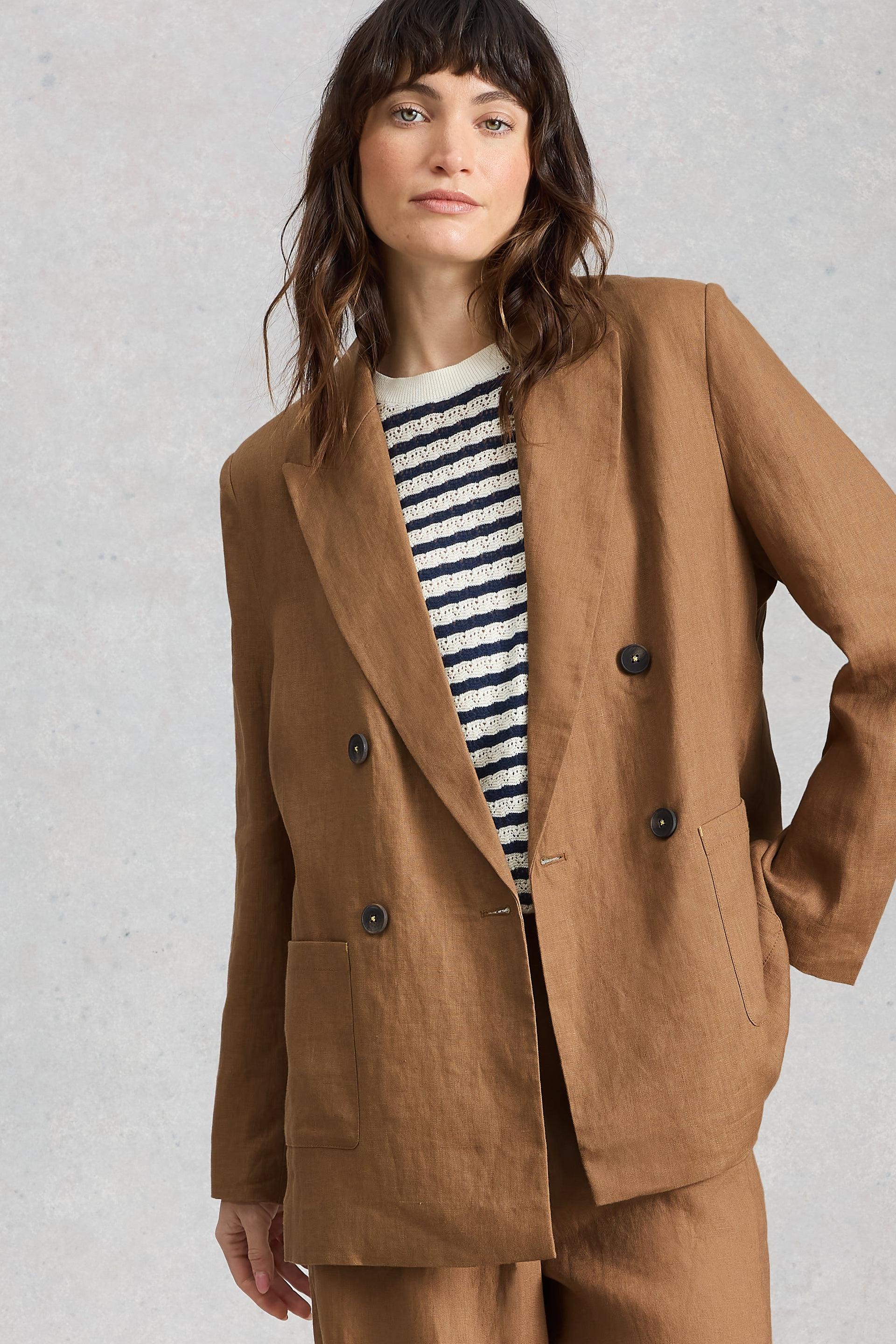 Woman wearing a brown linen blazer over a striped shirt on a light gray background