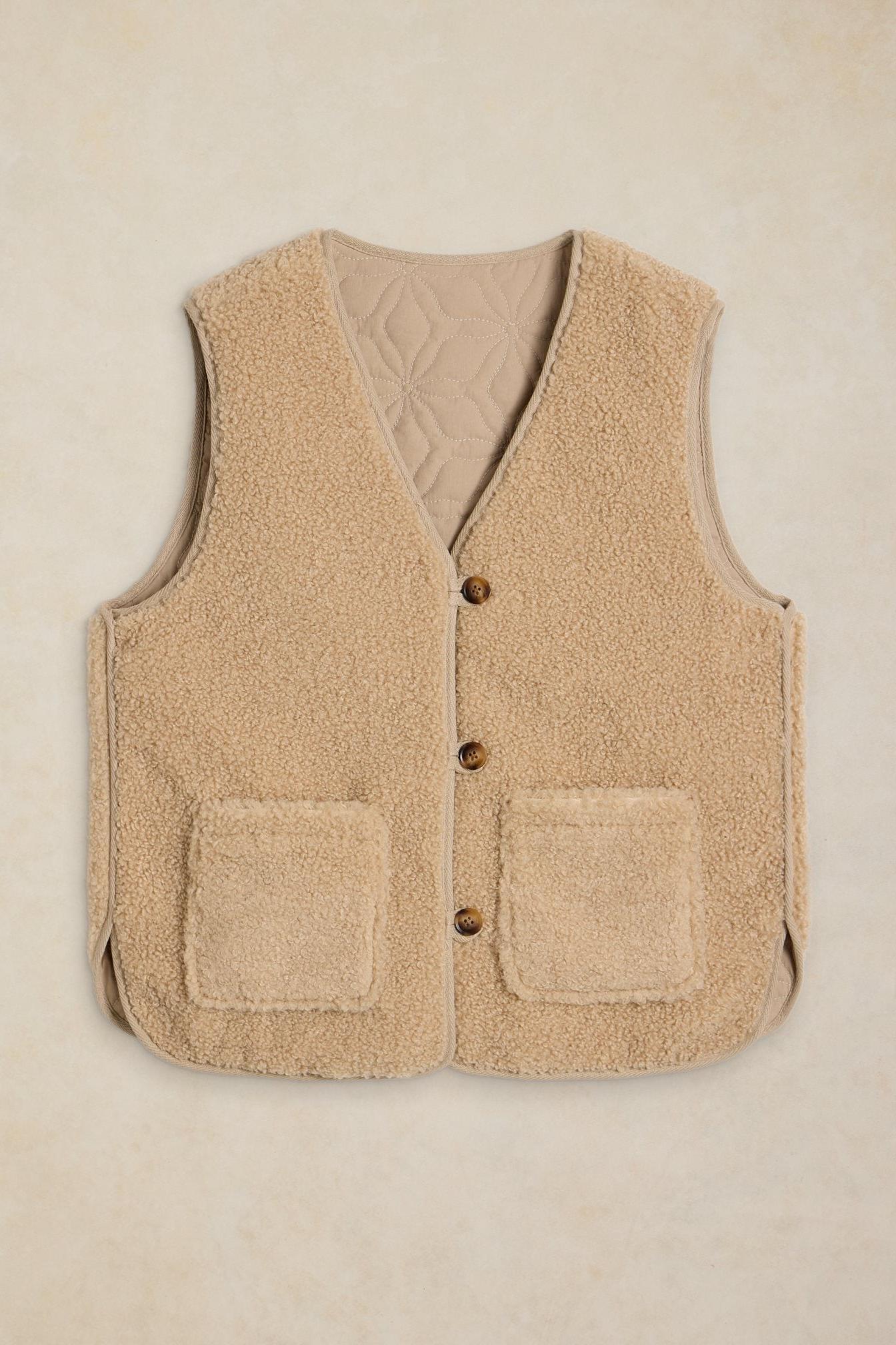 Beige women's reversible gilet featuring soft fleece texture and button-up front on a neutral background.