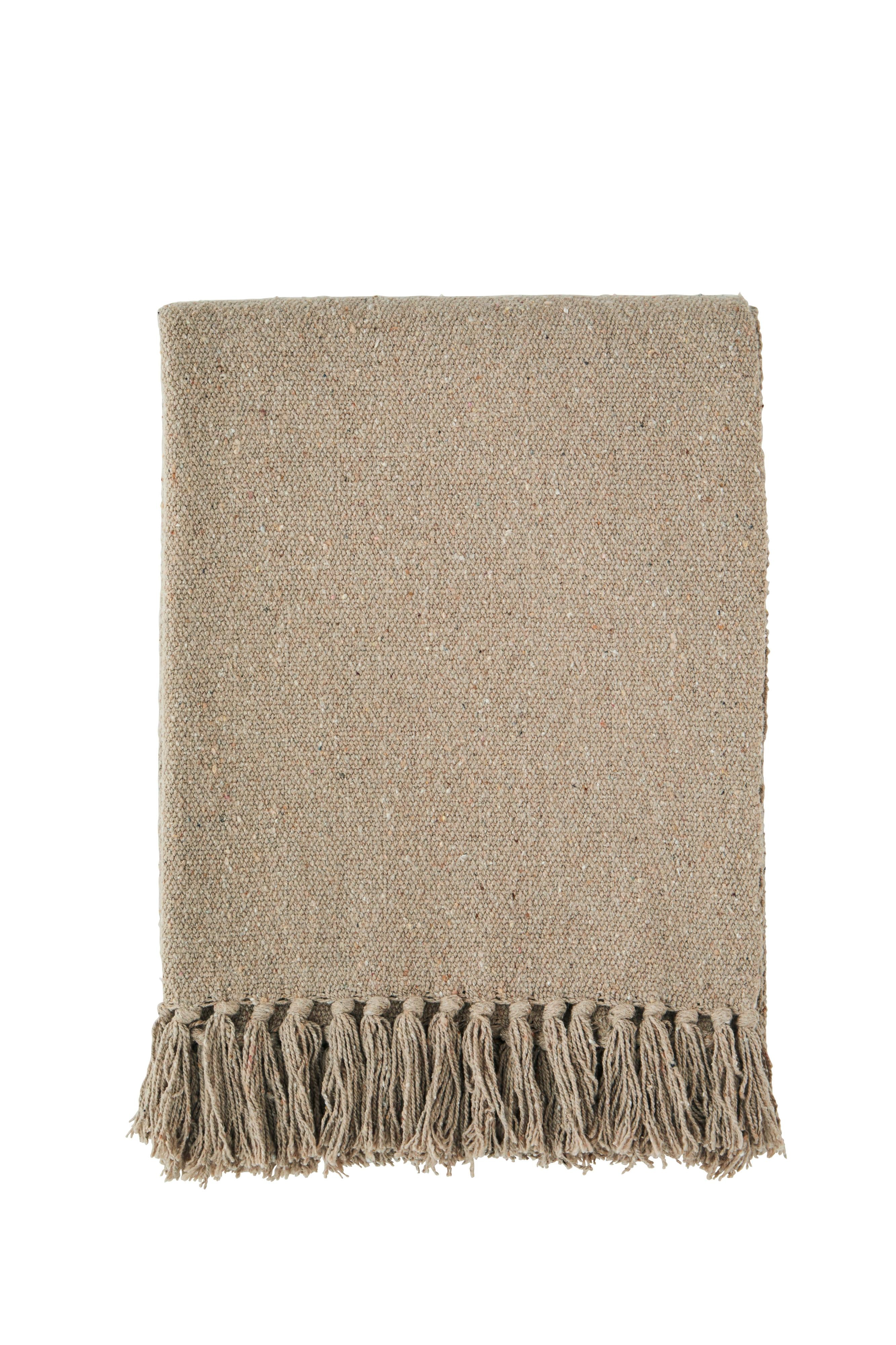 A folded beige woven cotton throw blanket with decorative fringe tassels isolated on a white background.