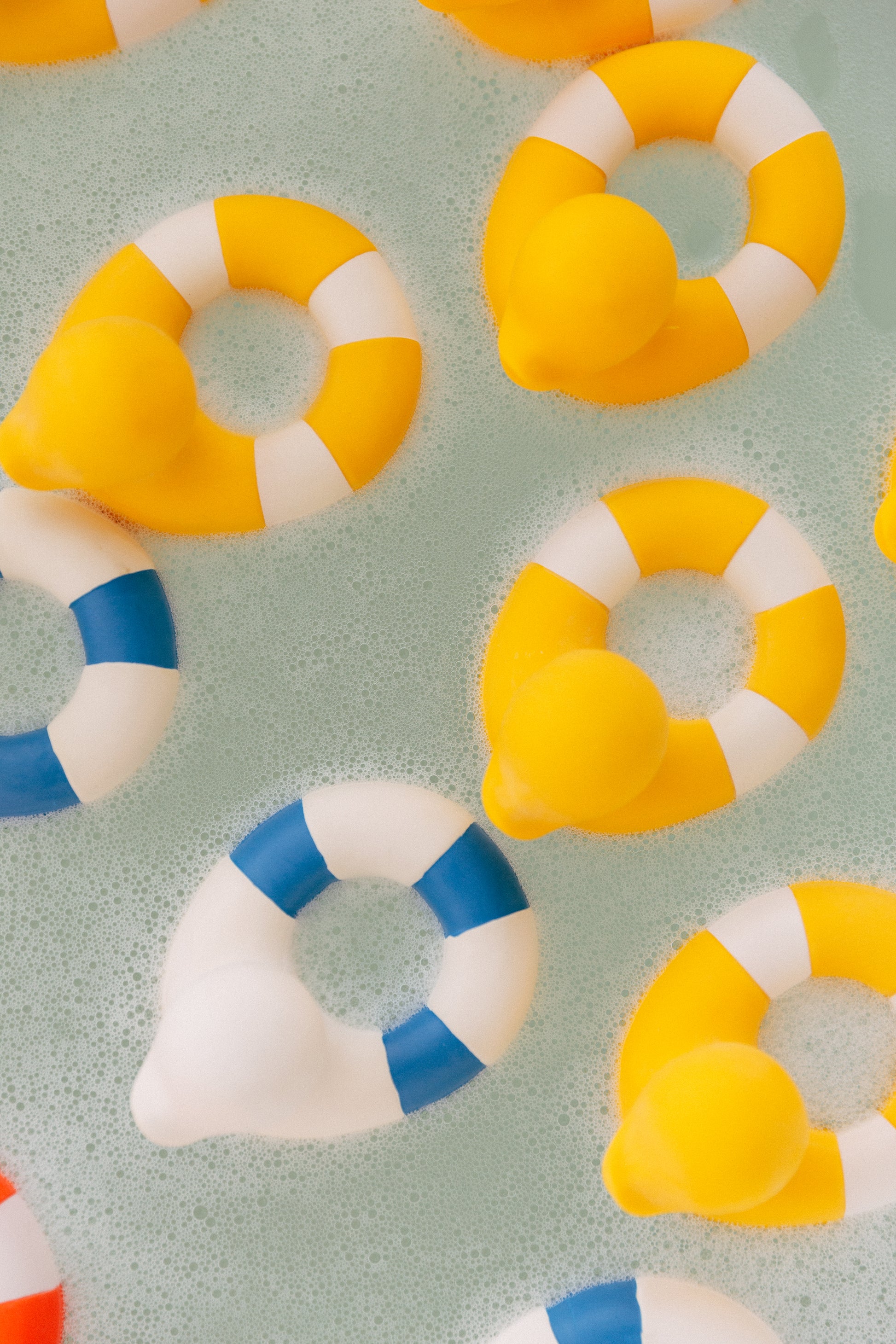 Baby bath toy and teether, Flo the Floatie Yellow, floating in a bath.