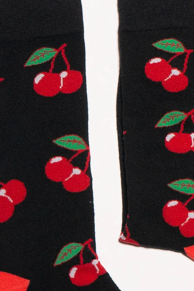A pair of black socks with a repeating red cherry print pattern made from bamboo